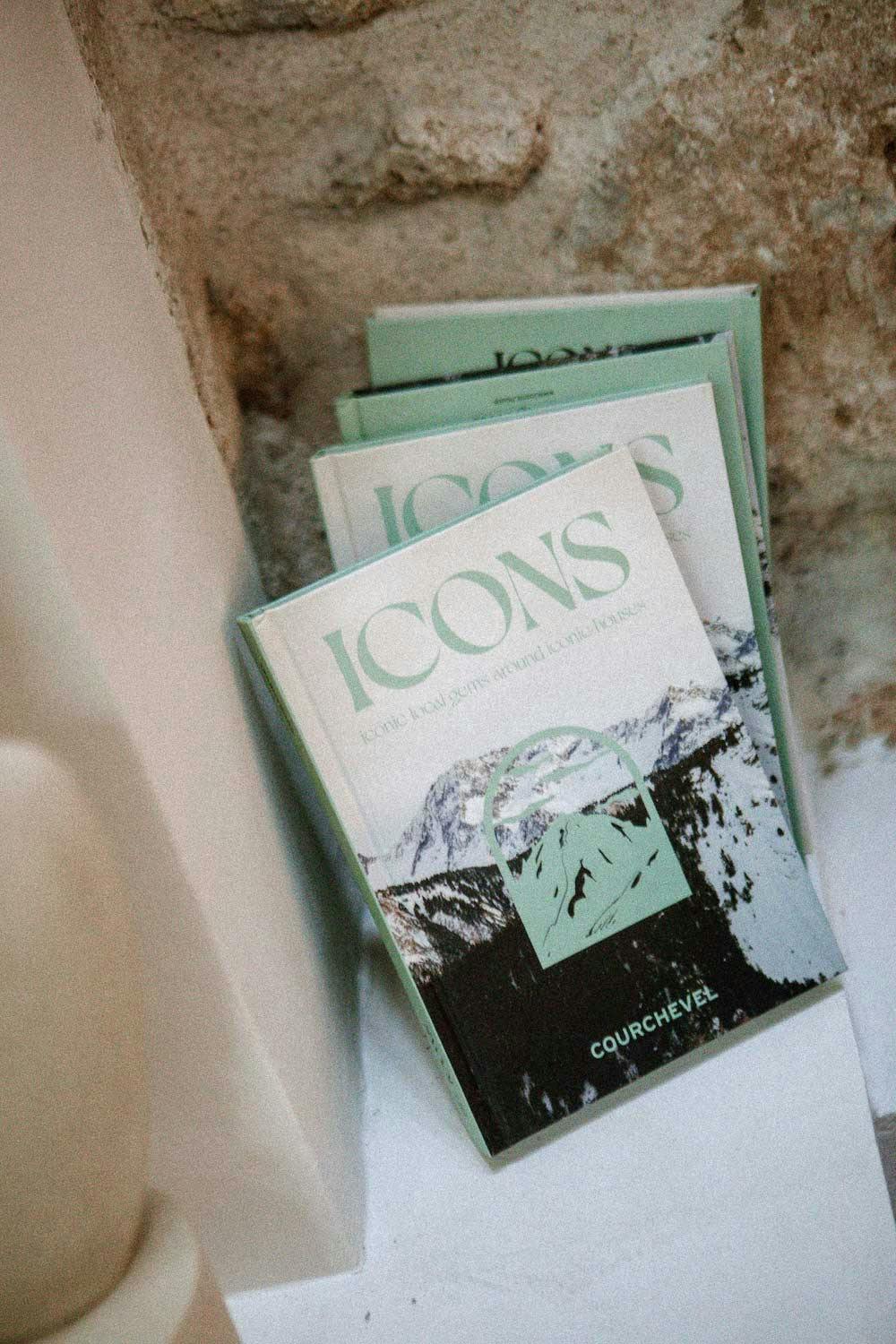 3 copy of "Icons, Courchevel" book standing against a stone wall