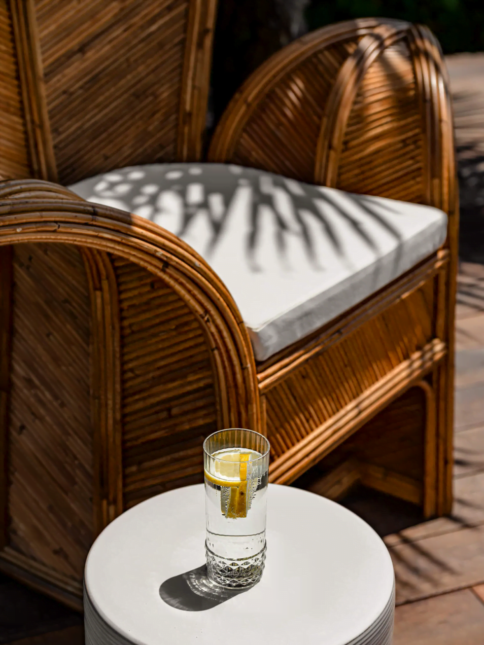 Ambiance - gros plan sur une grande chaise à l'extérieur de la villa et verre d'eau avec du citron vert sur une table aux Bords du Lac