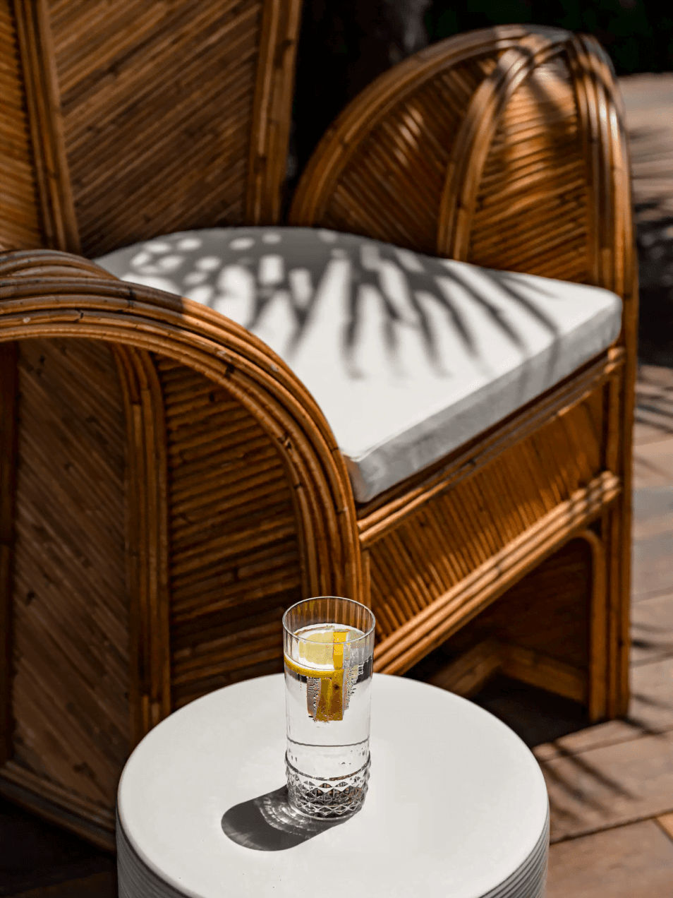 Ambiance - gros plan sur une grande chaise à l'extérieur de la villa et verre d'eau avec du citron vert sur une table aux Bords du Lac