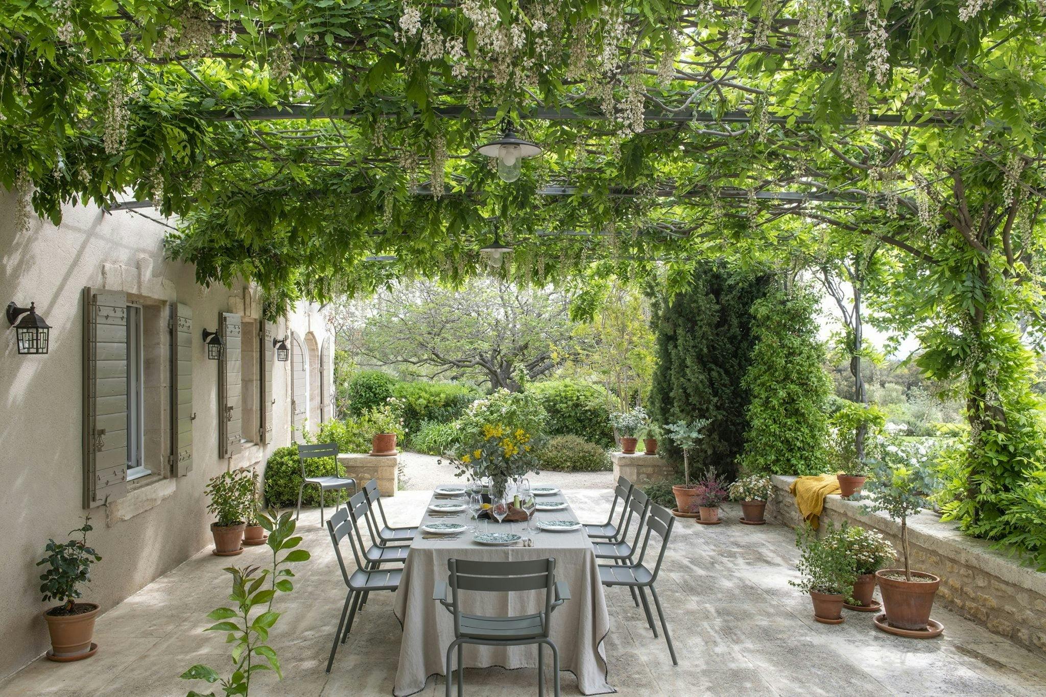 Country house, outdoor table and chairs under pergola with trees