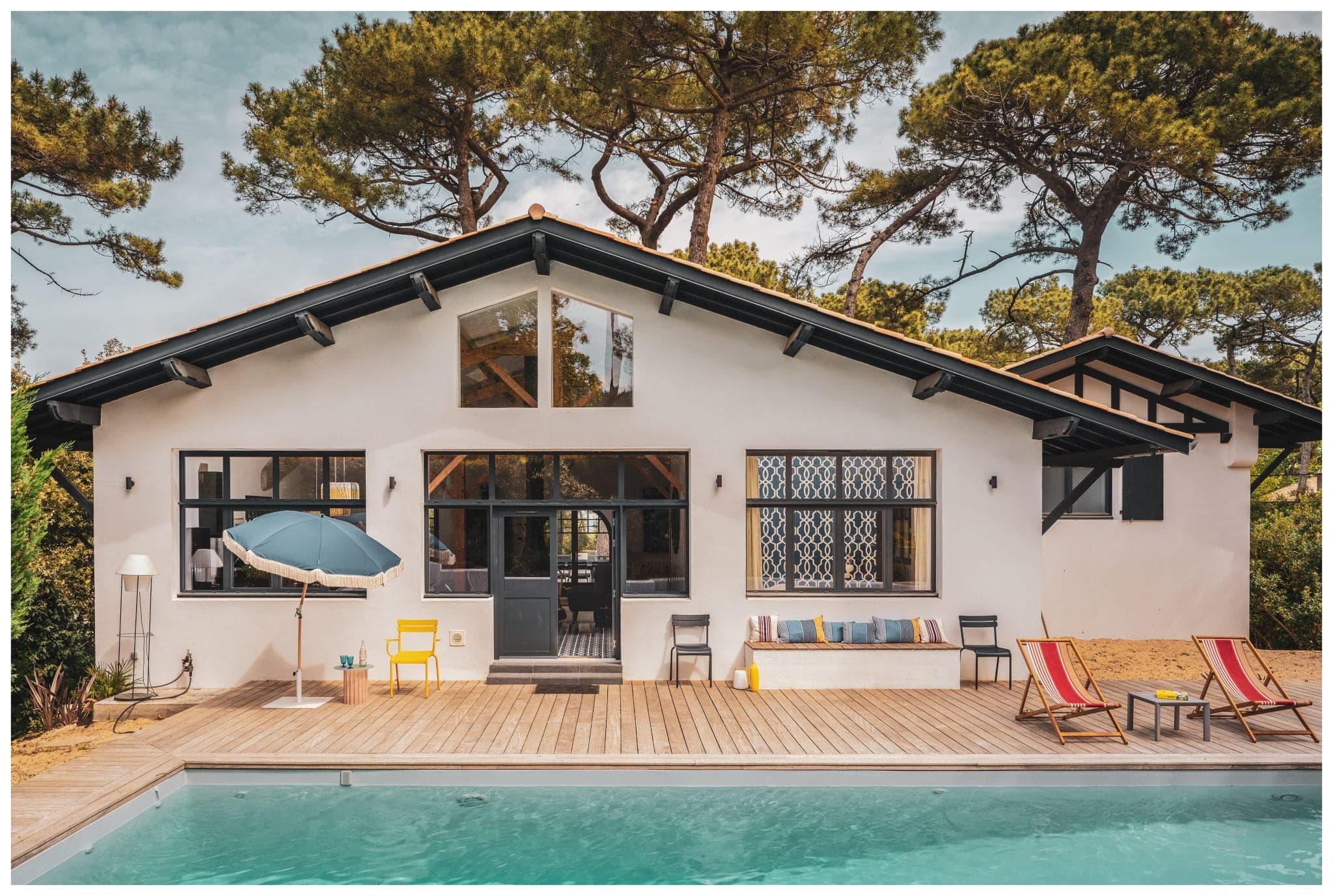 view of the villa, pool and deckchairs