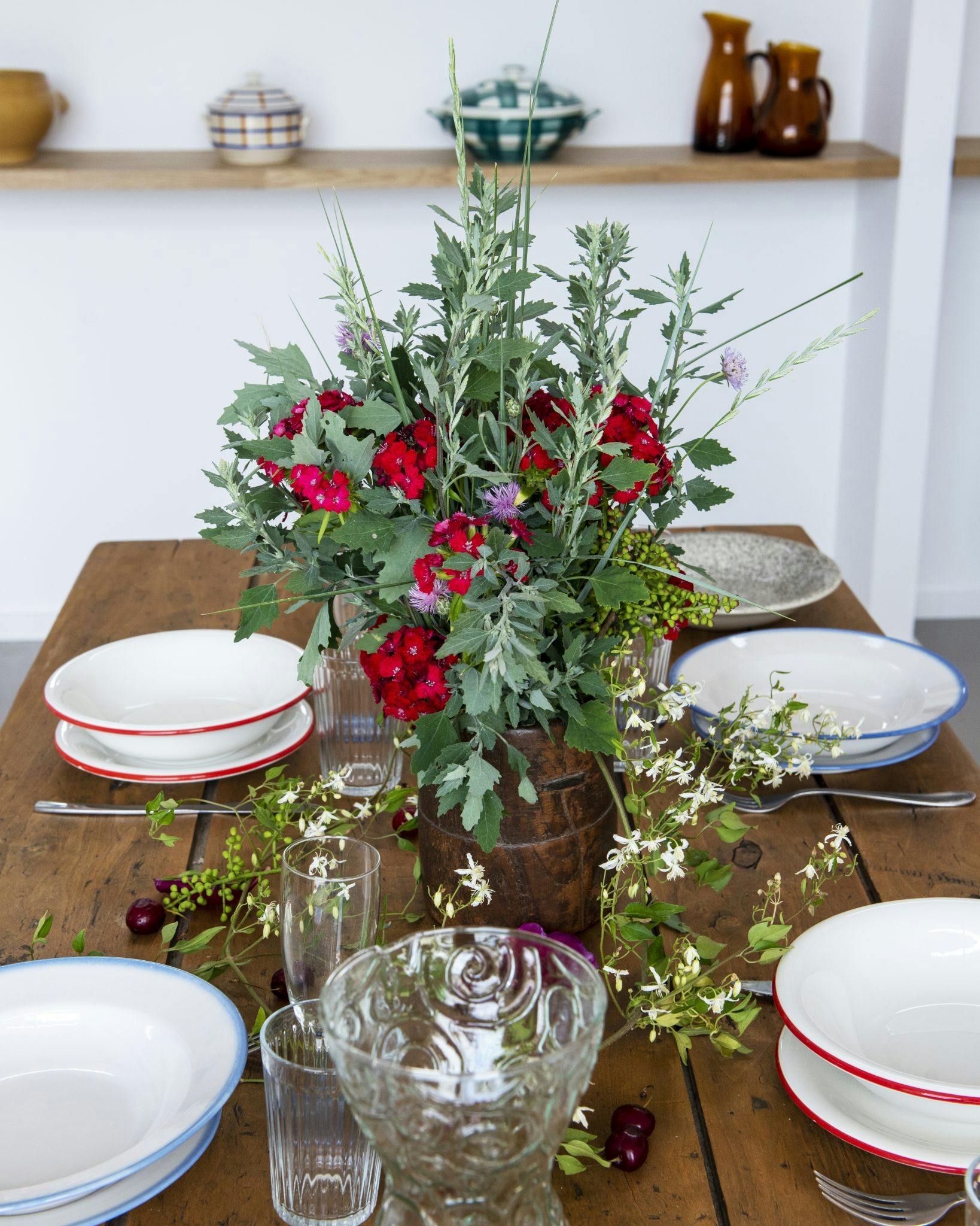 Table de ferme préparée dans la salle à manger de l'Atelier des Milles Roches avec un grand bouquet de fleurs central