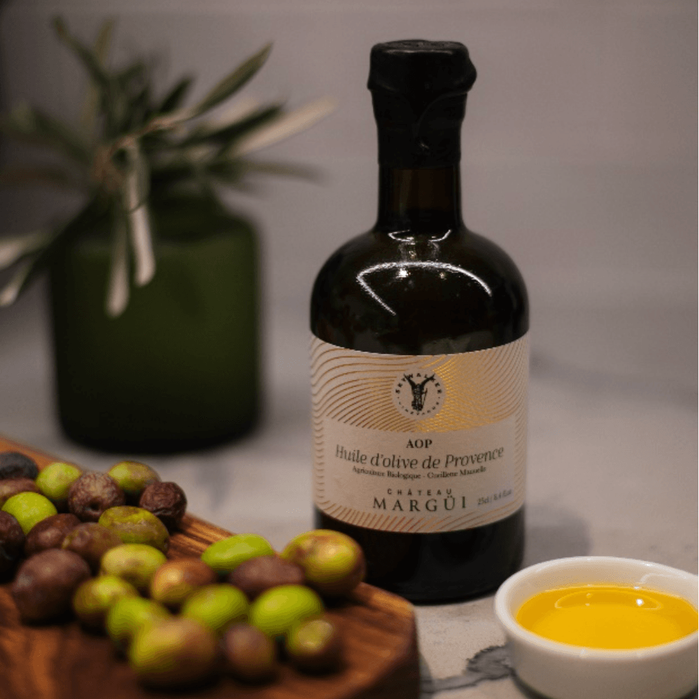 Bottle of Chateau Margüi olive oil with a few olives aside