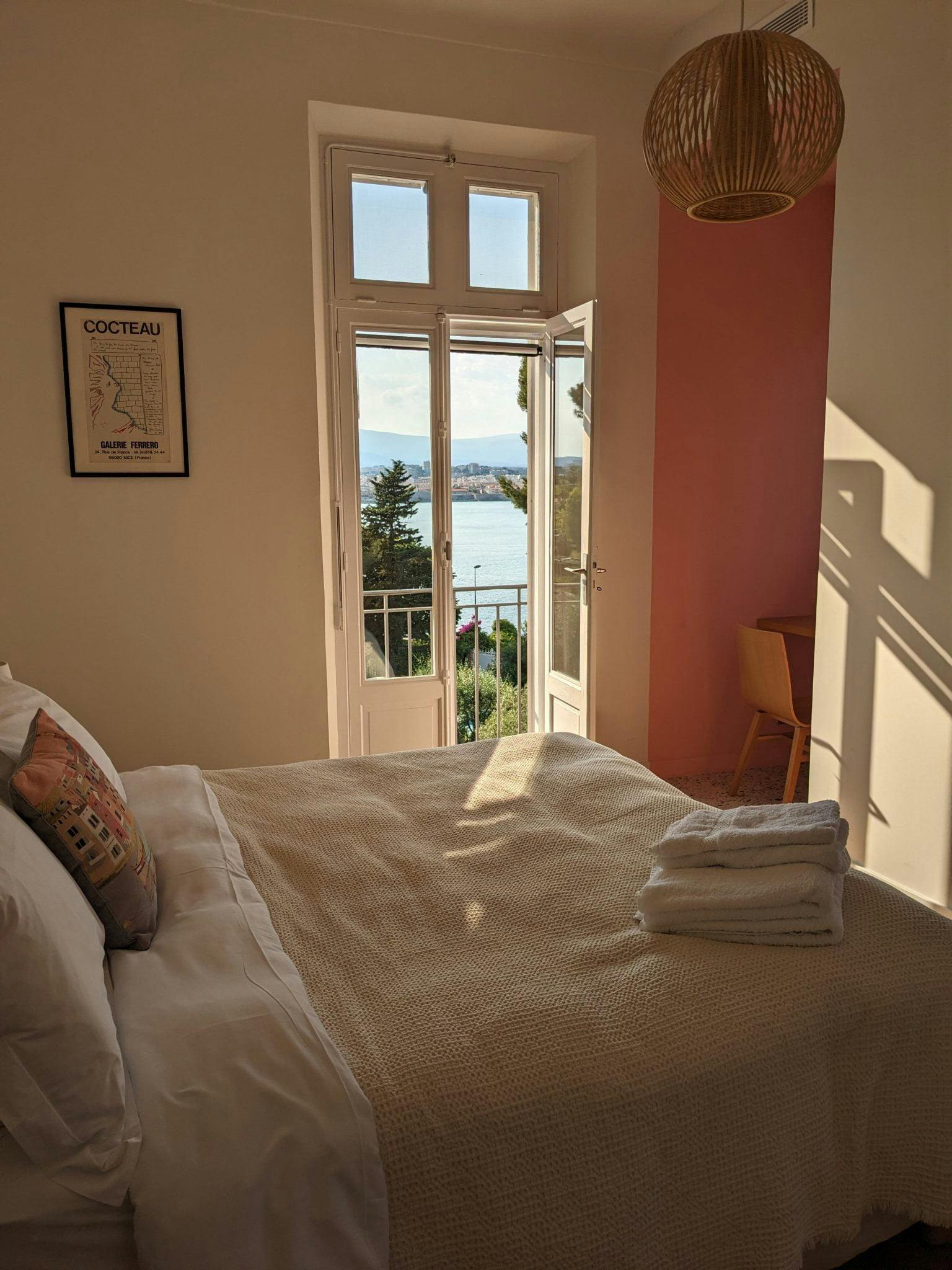 Sunbeam in the pink bedroom, bed made with towels laid on top, beautiful light