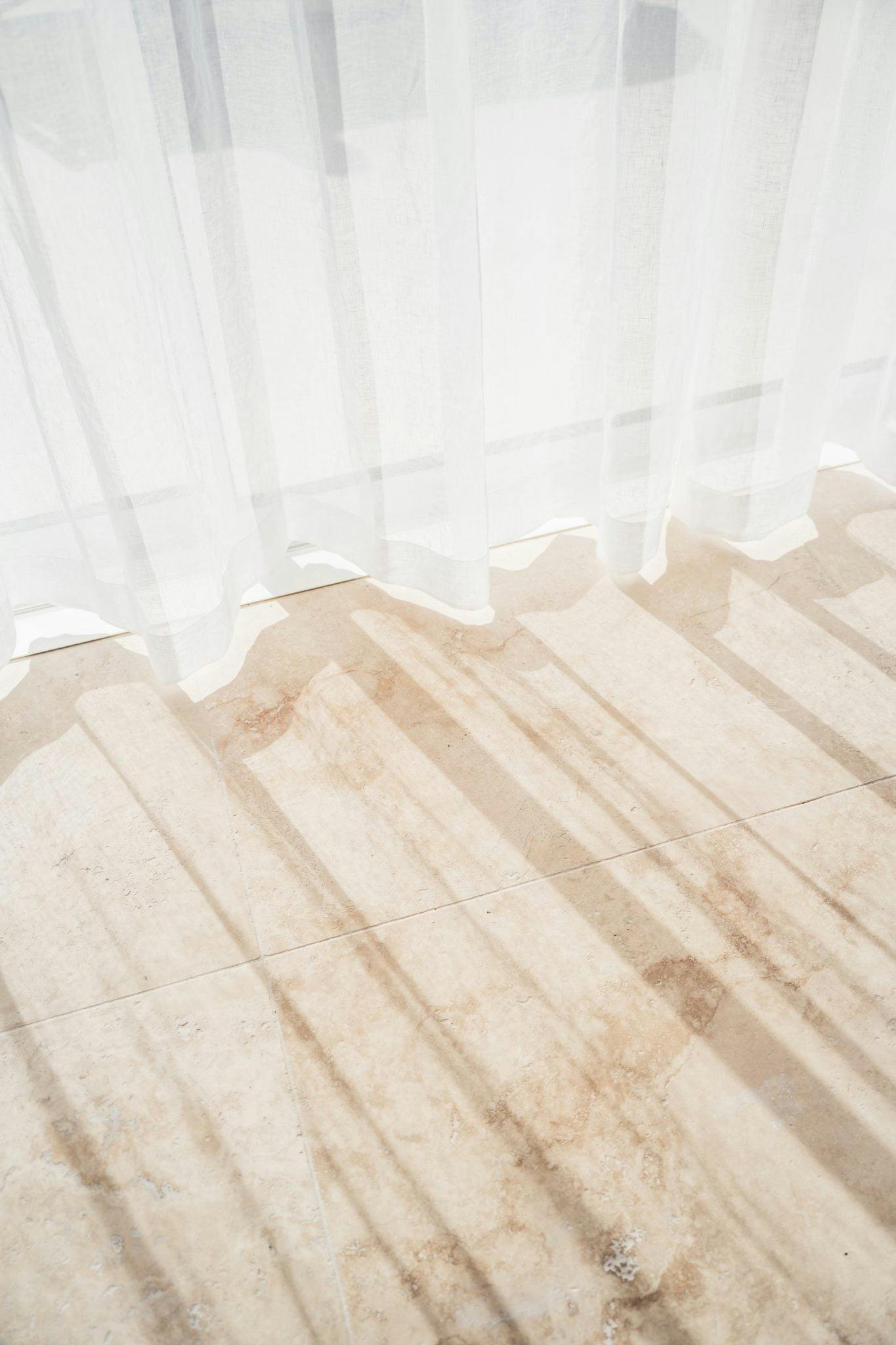 Detail of the light streaming onto the floor through the curtains, casting shadows