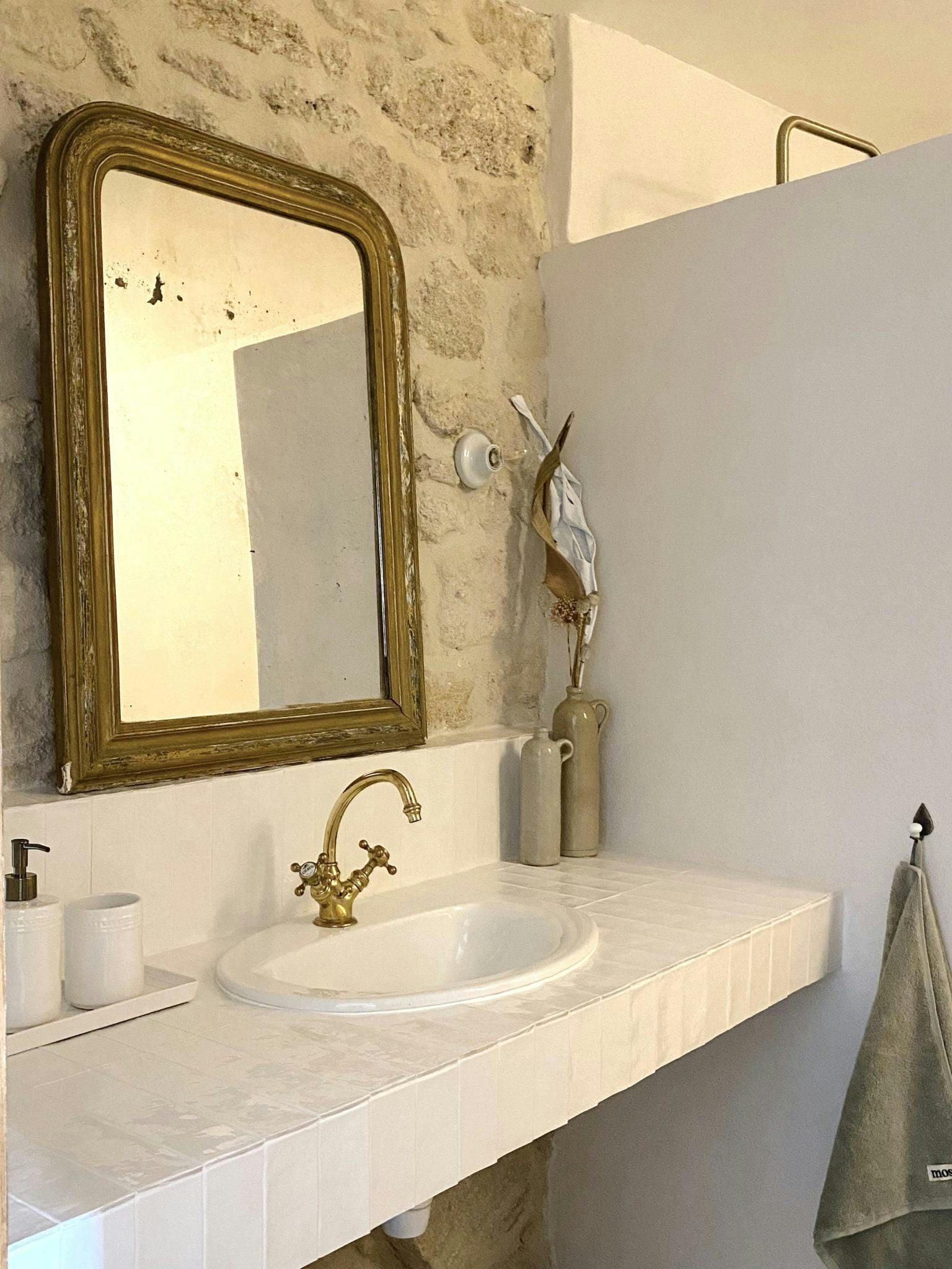 Antique washbasin and mirror set against a backdrop of stone and earthenware walls