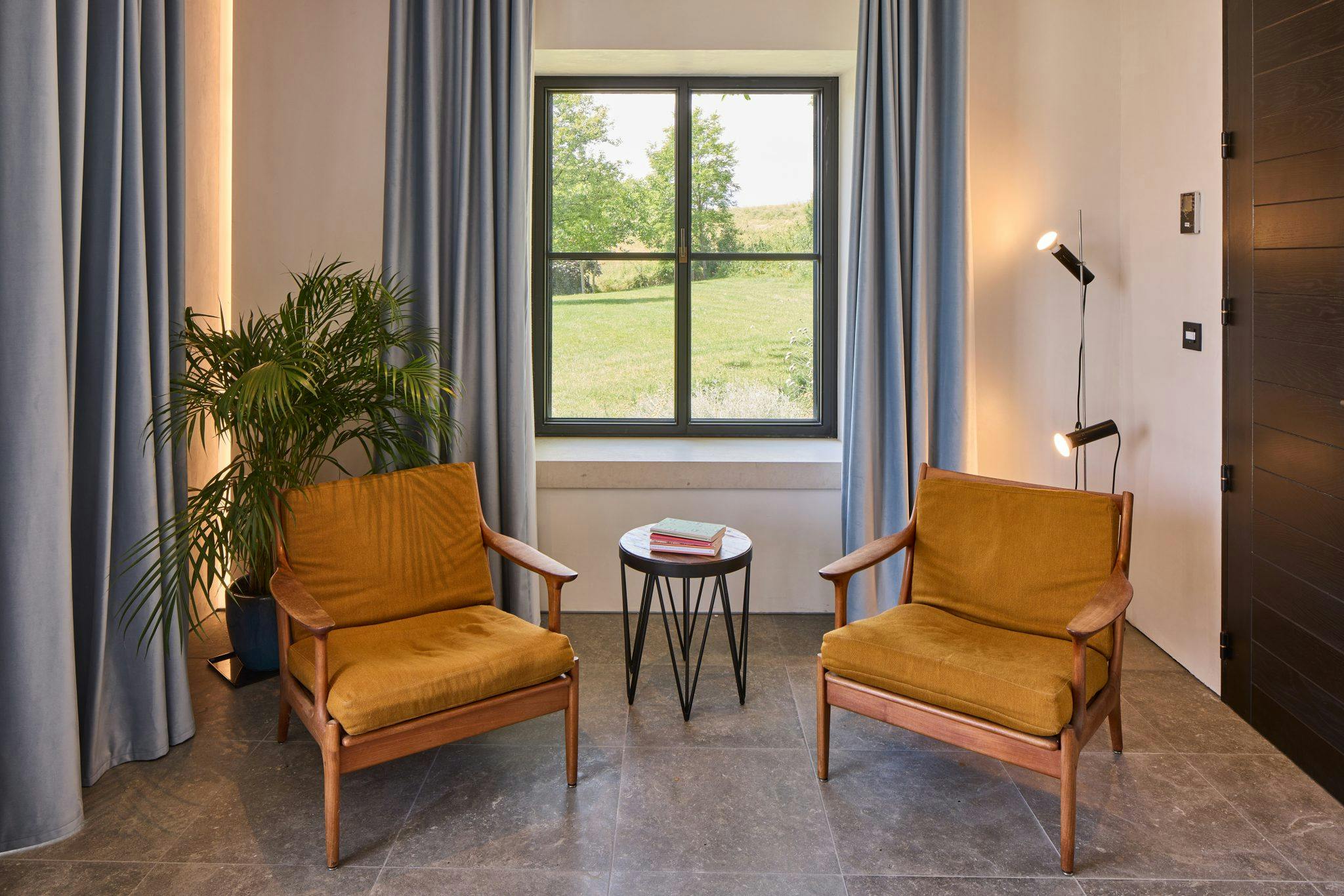 Two mid-century armchairs in front of a window overlooking nature
