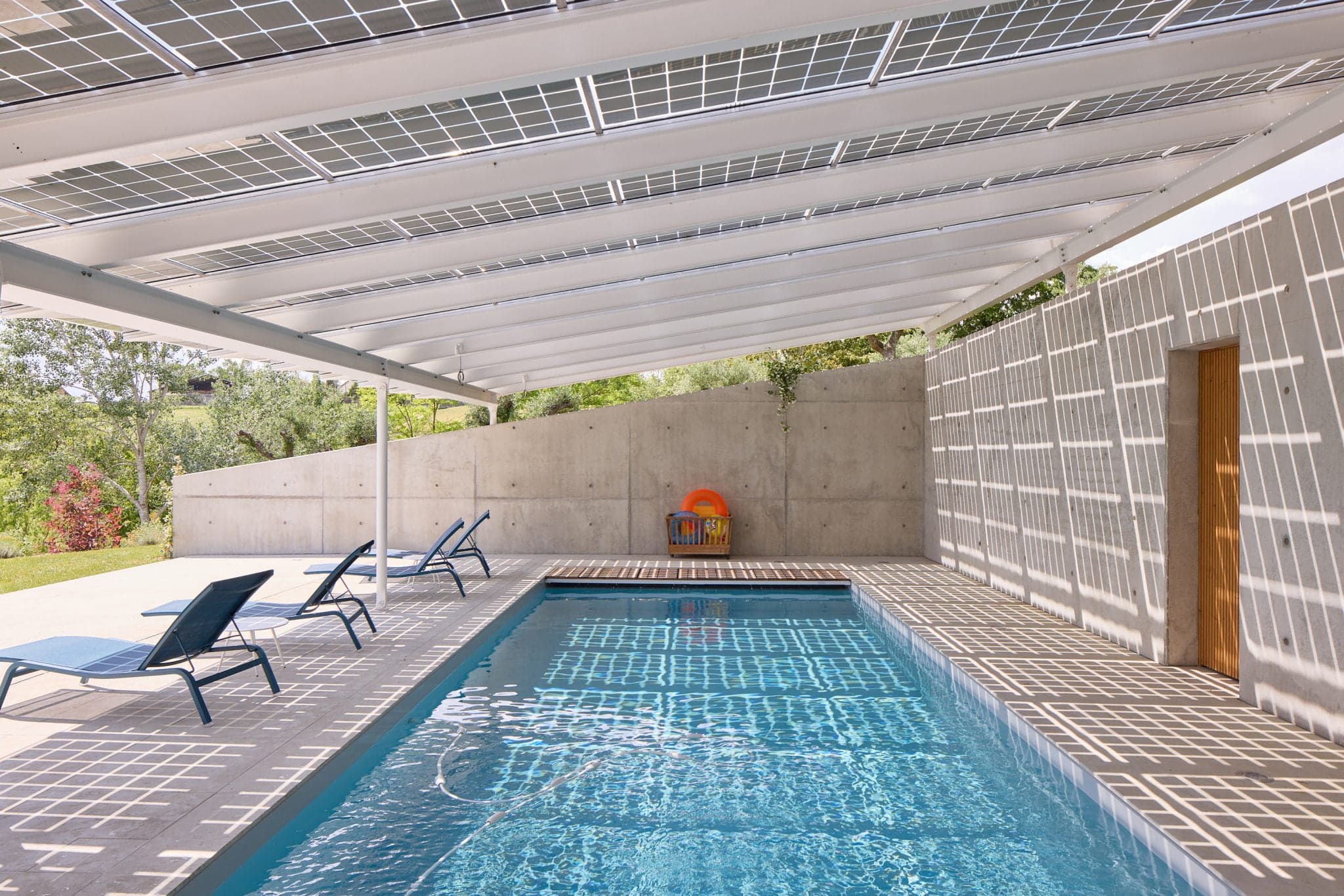 Swimming pool under awning, view of toy box and deckchairs