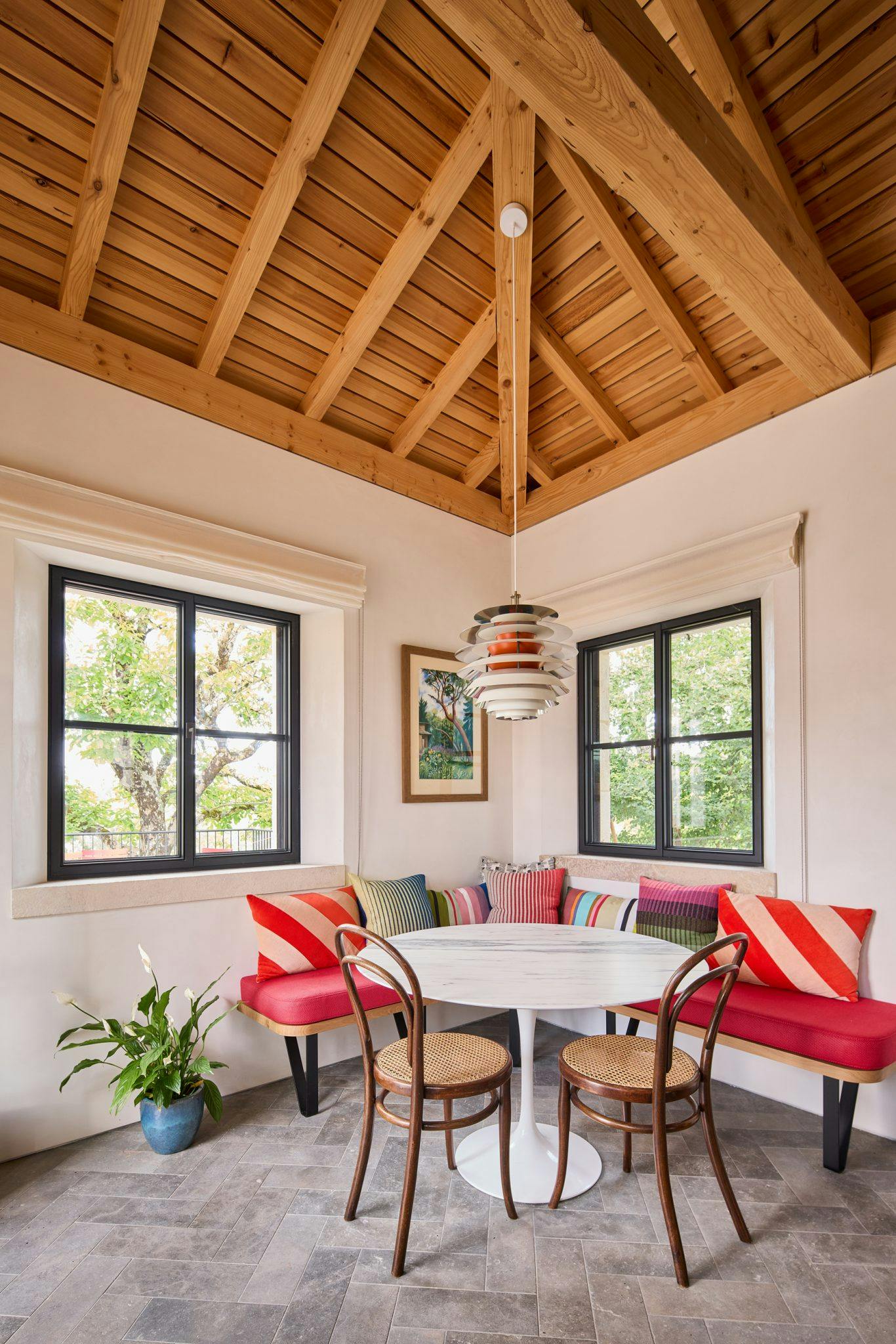 Dining area, high ceiling with wooden beams, benches covered with red cushions