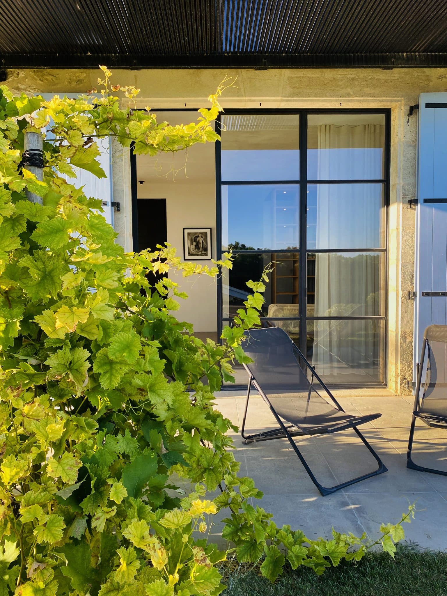 Chaise longue amidst greenery in front of a bay window