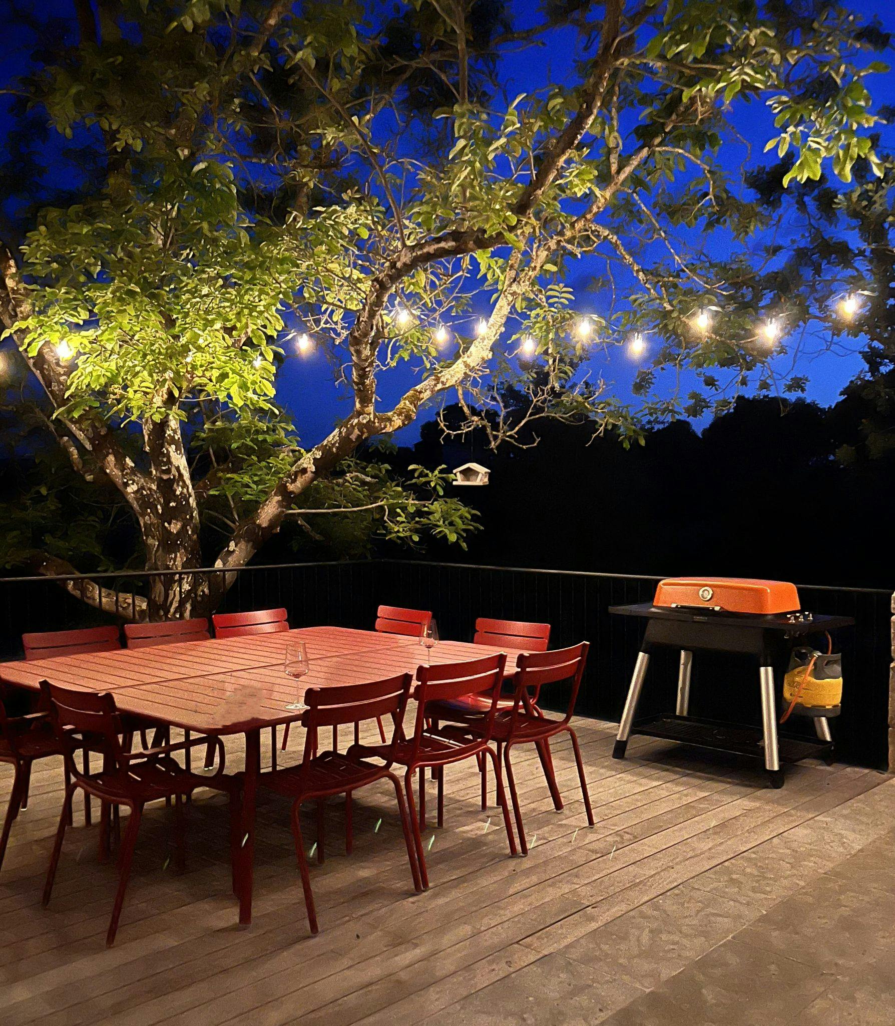 Terrace at night, red table illuminated by garland