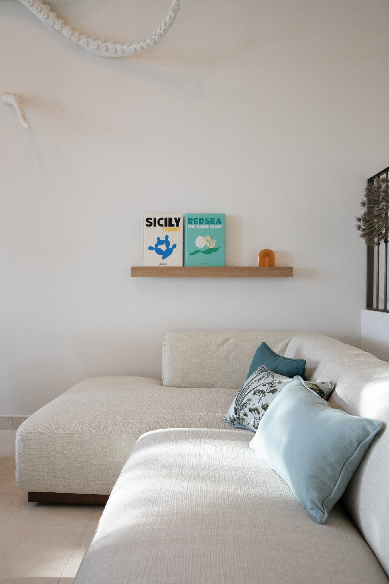 Living room: modern white sofa and blue-toned decoration (cushions and books)