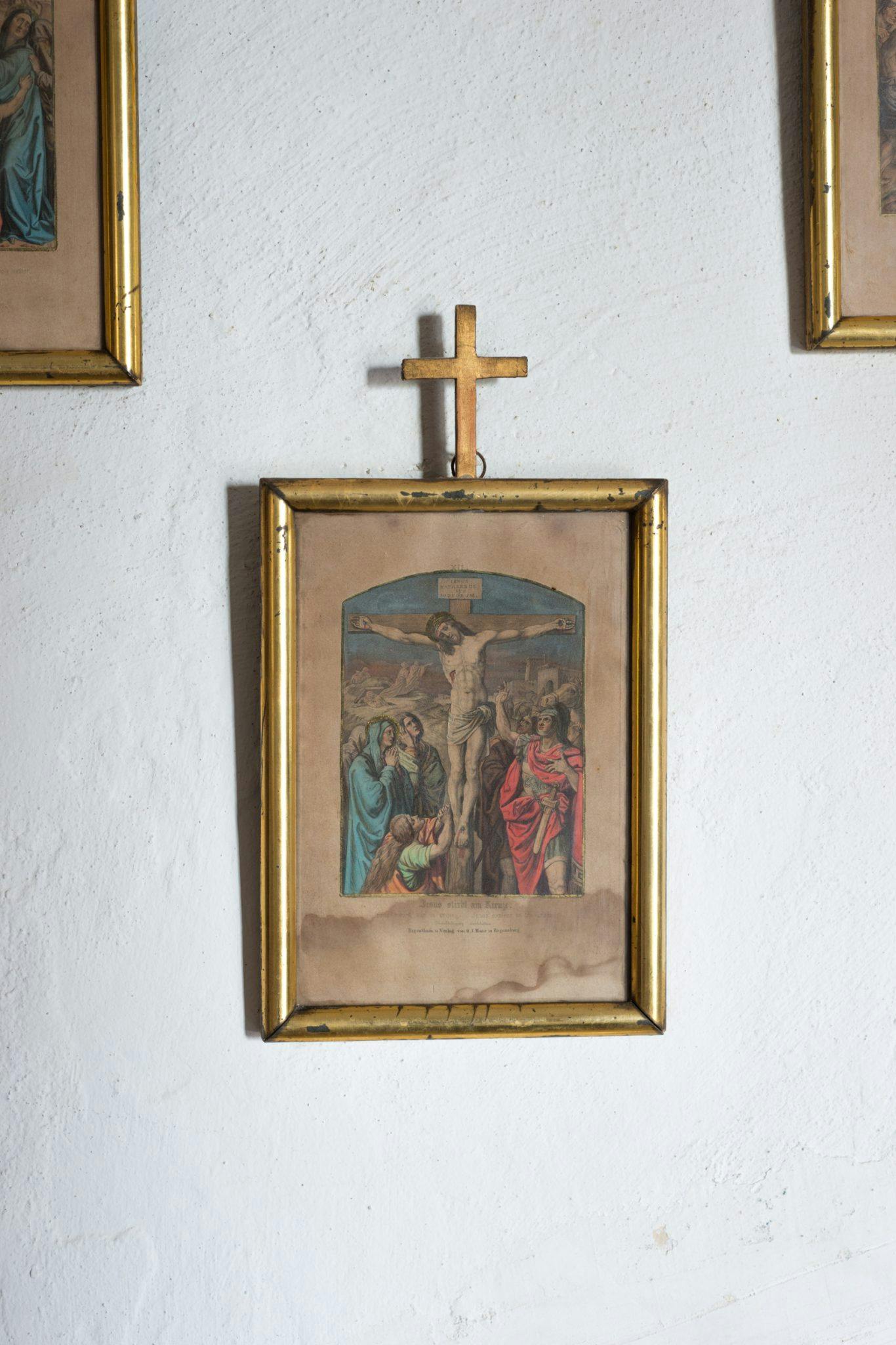 Antique painting hanging on the wall, surmounted by a cross