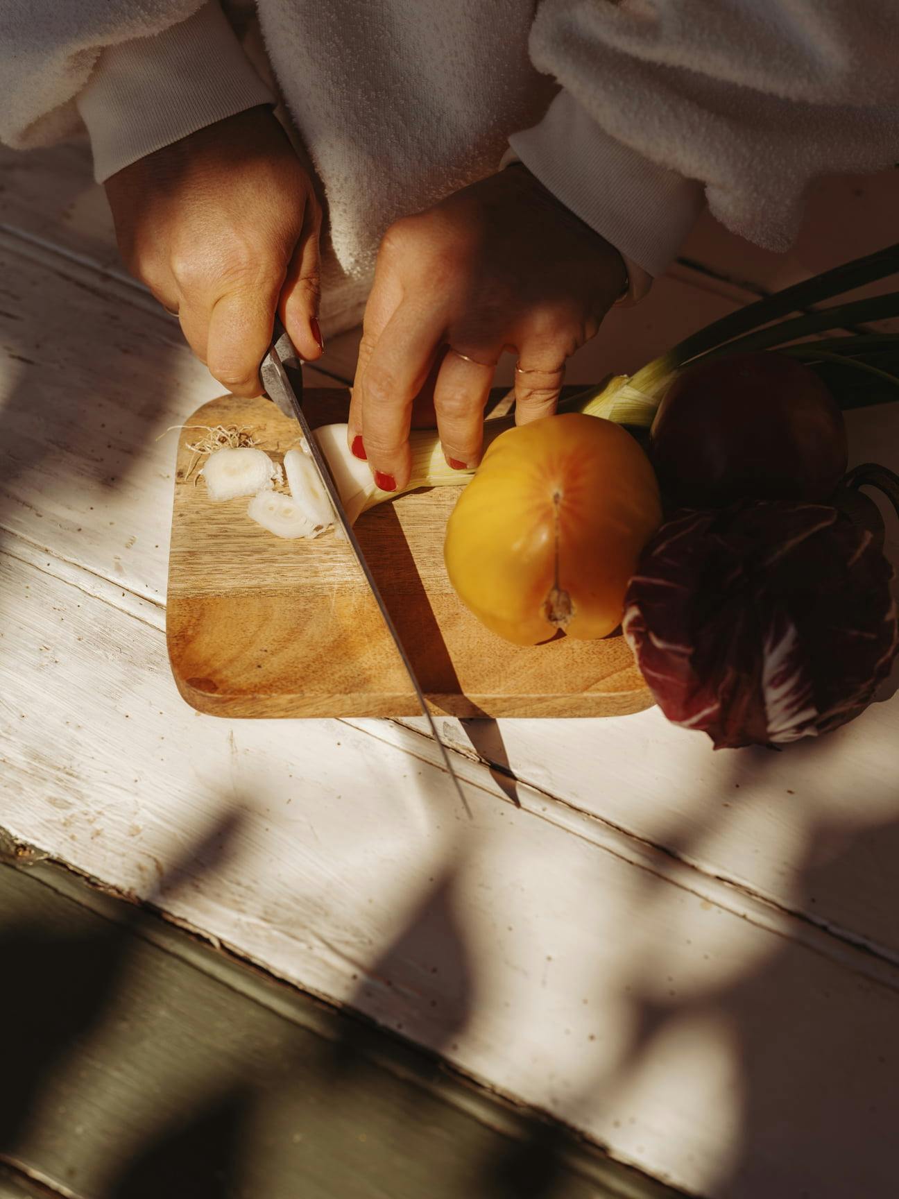 Emmanuelle's hands cutting garlic on a wooden board