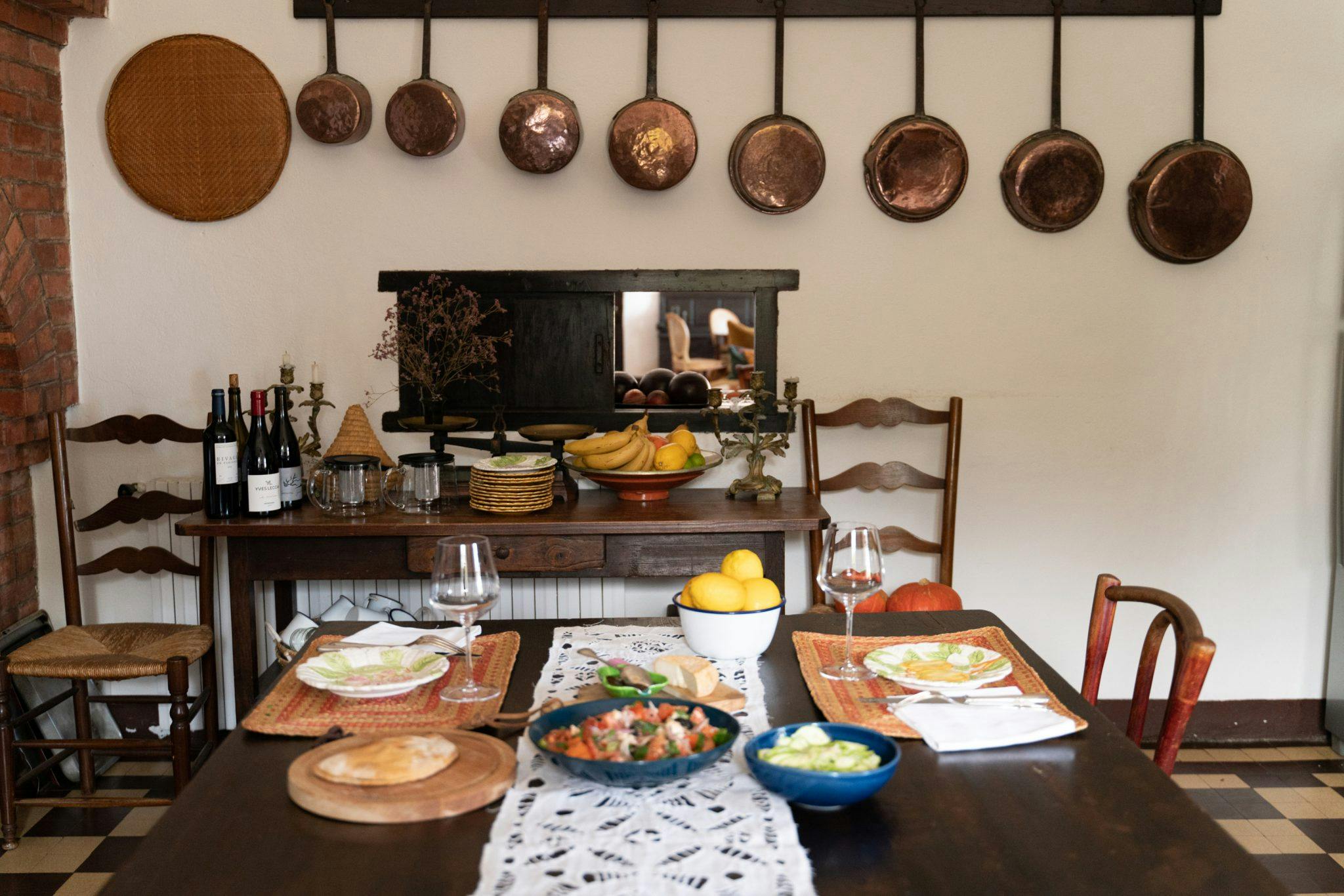 Kitchen: hanging copper pots and pans, wooden table garnished with delicacies
