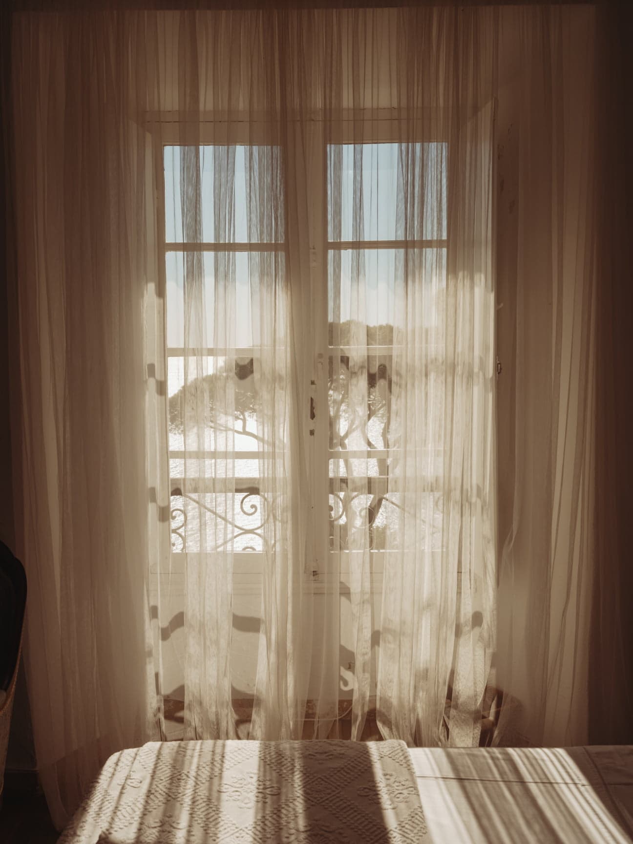 Sunlight shining through the light curtains onto the bed in one of the bedrooms