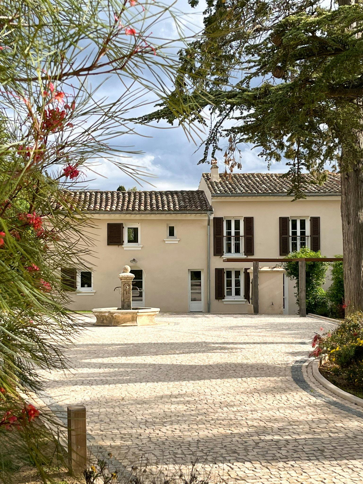 Paved path to the bastide with its small fountain, lined with shrubs