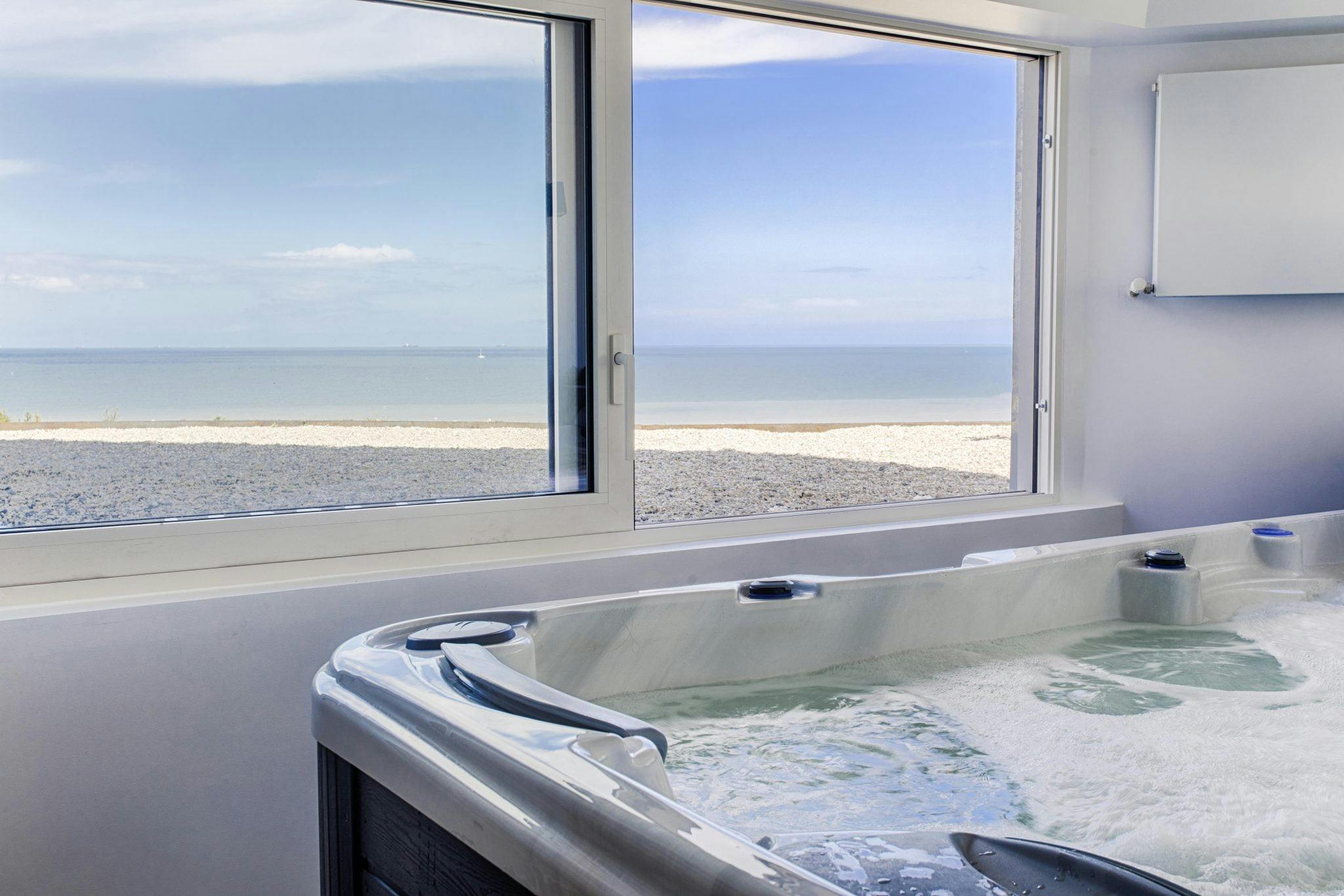 The jacuzzi overlooks an open window and the sea
