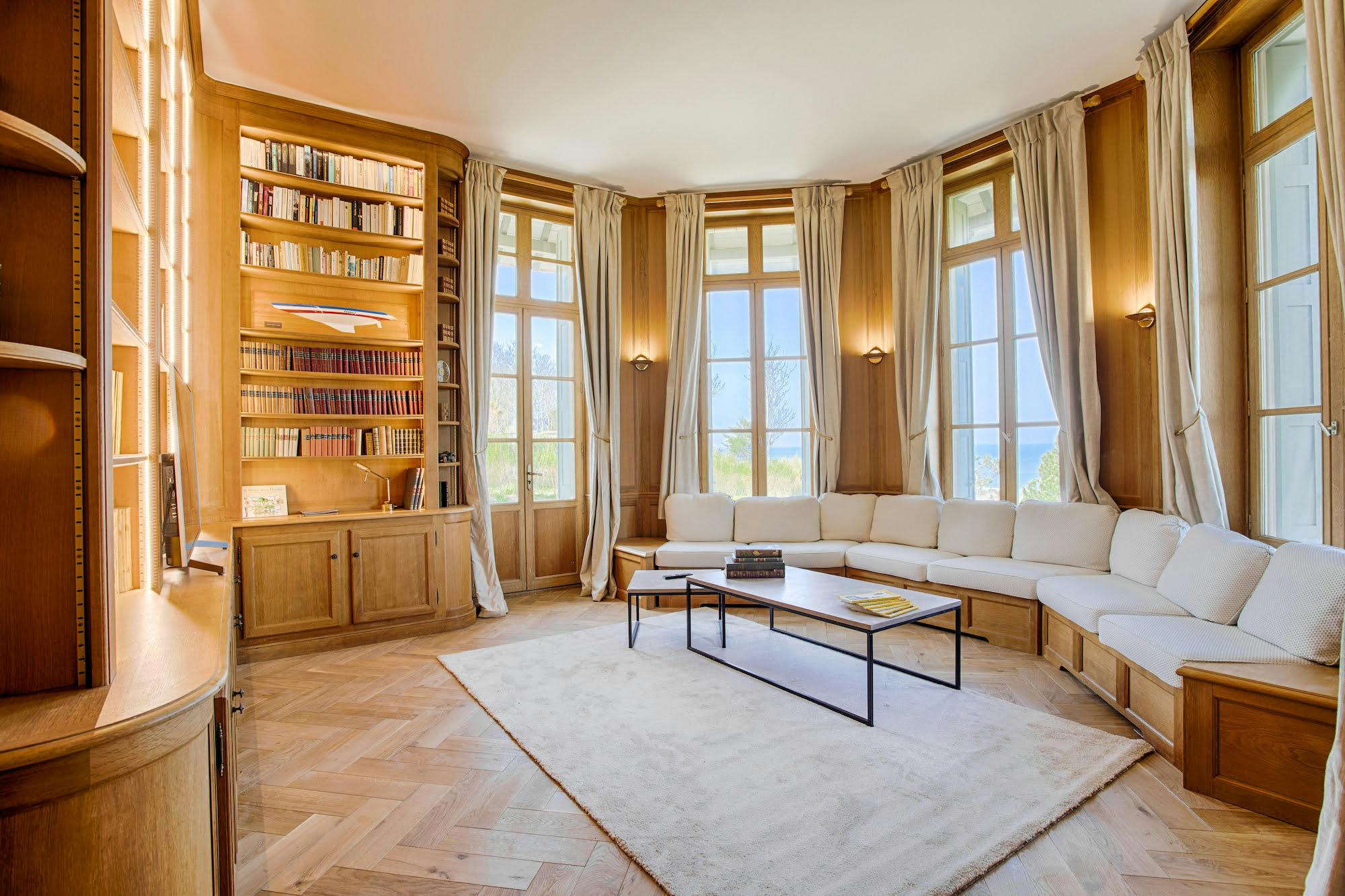 A cozy, wood-paneled library with a view of the sea