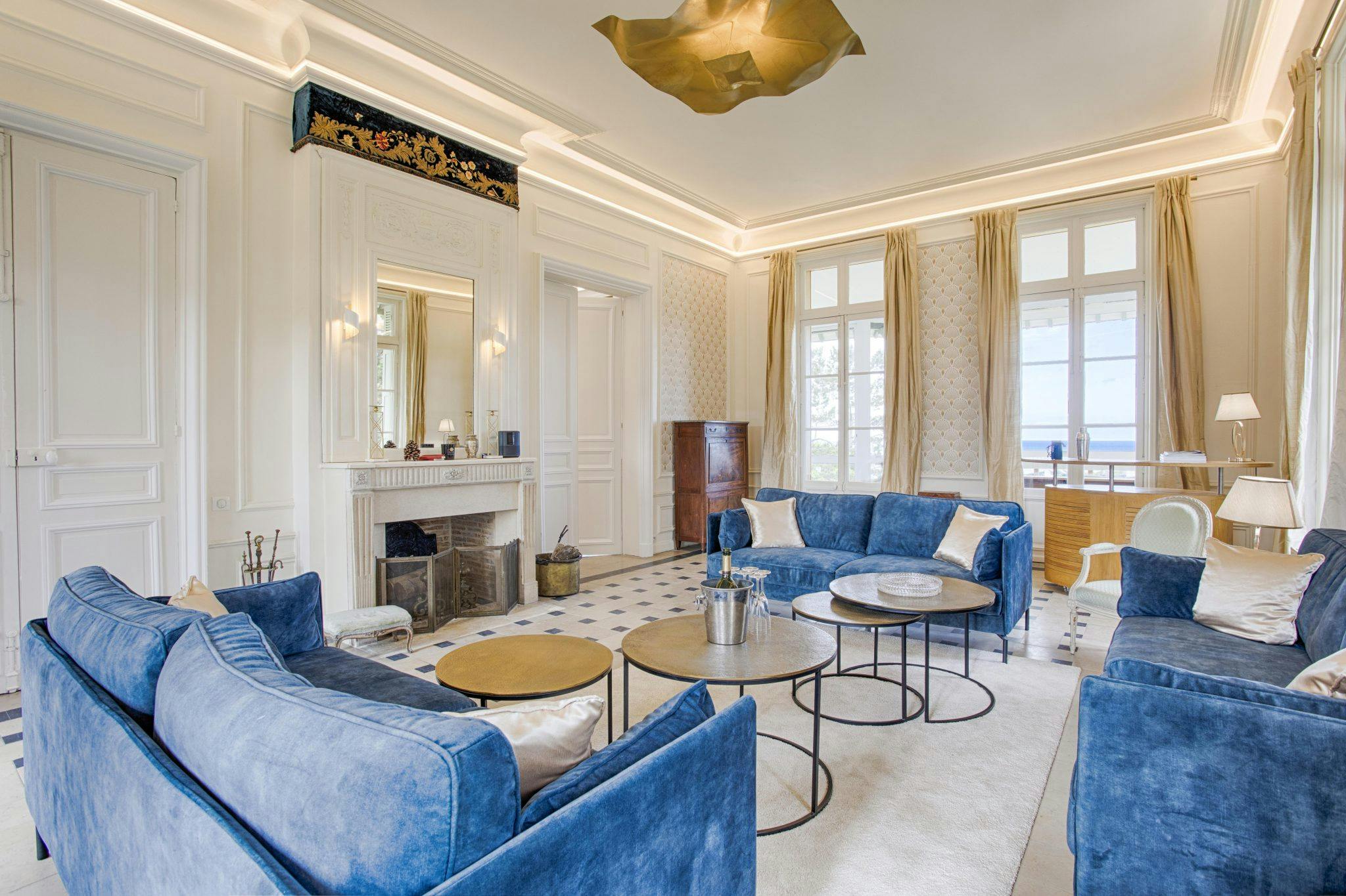 The living room at the Abbaye de Deauville, between tradition and modernity, blue sofas and fireplace