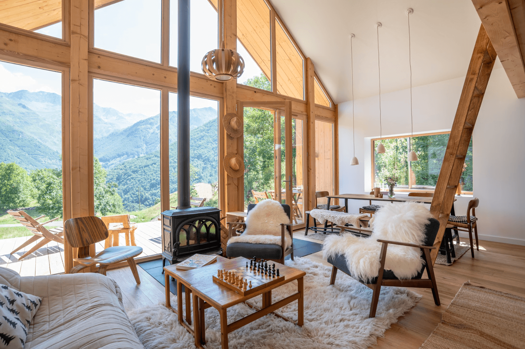 The living room of La Maison Refuge: large bay windows, armchairs with thick blankets, wood stove