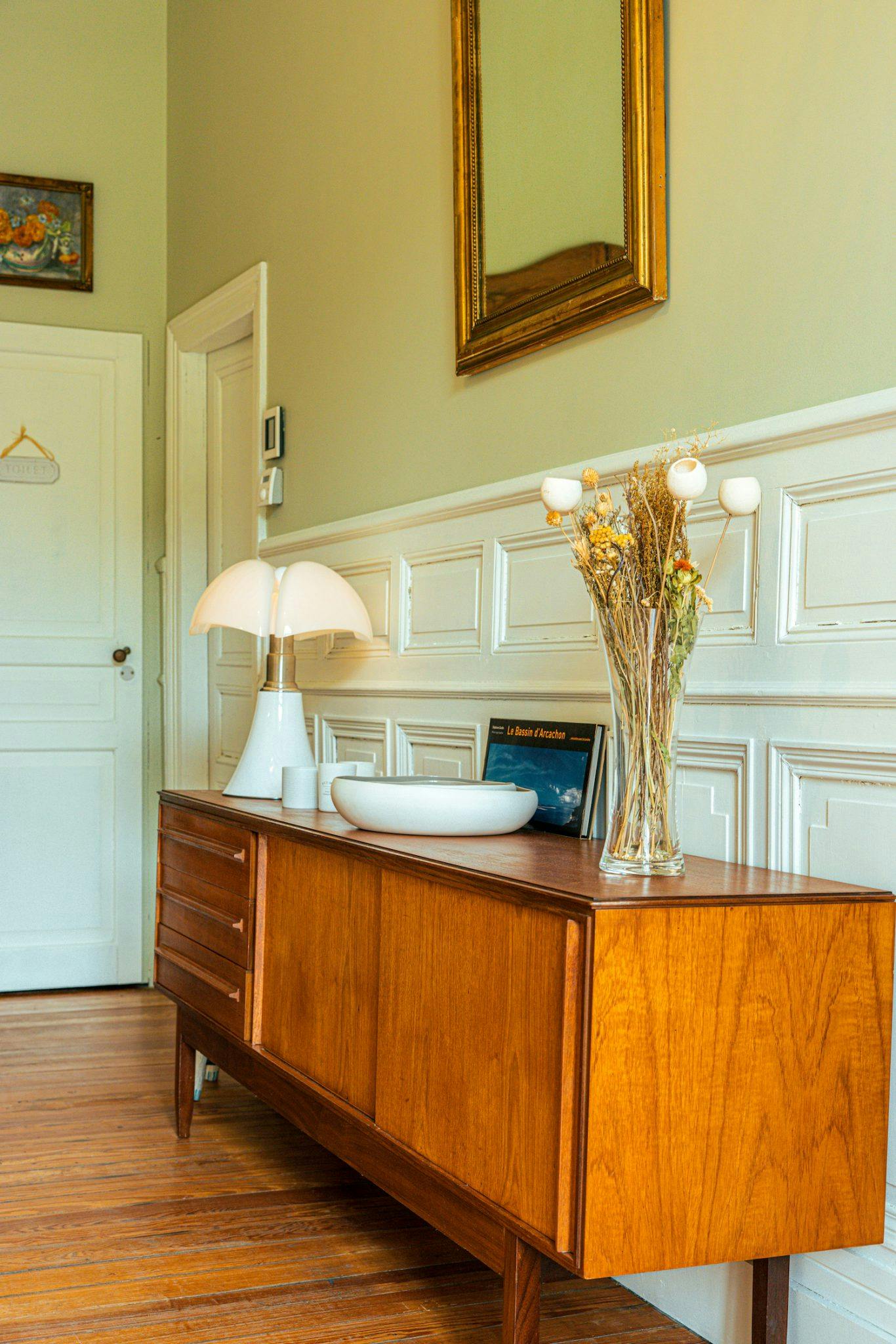 Vintage enfilade cabinet in the entrance hall with antique mouldings and frames, in a modern spirit