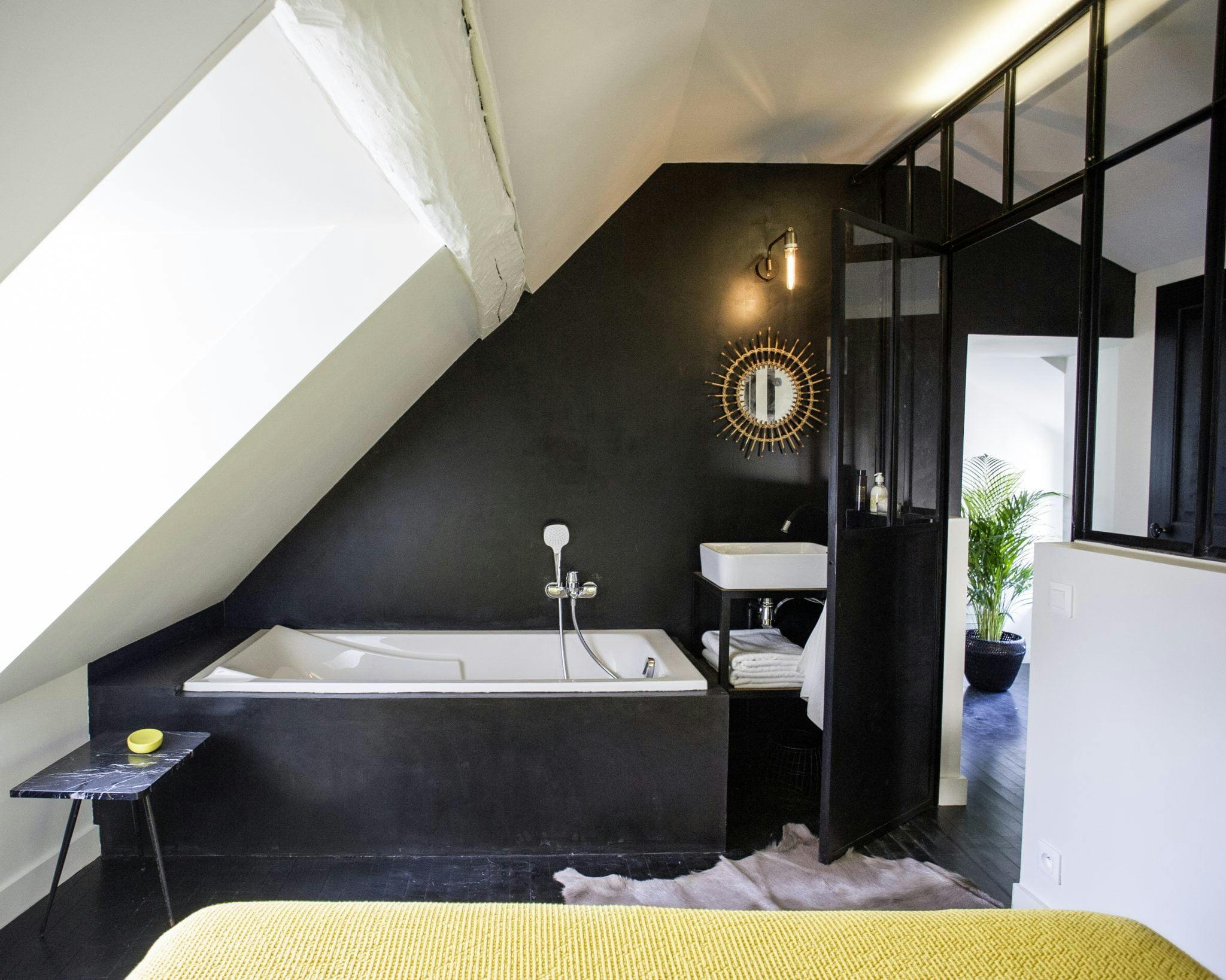 Detail of the bathroom with black walls, glass bay window, bathtub.