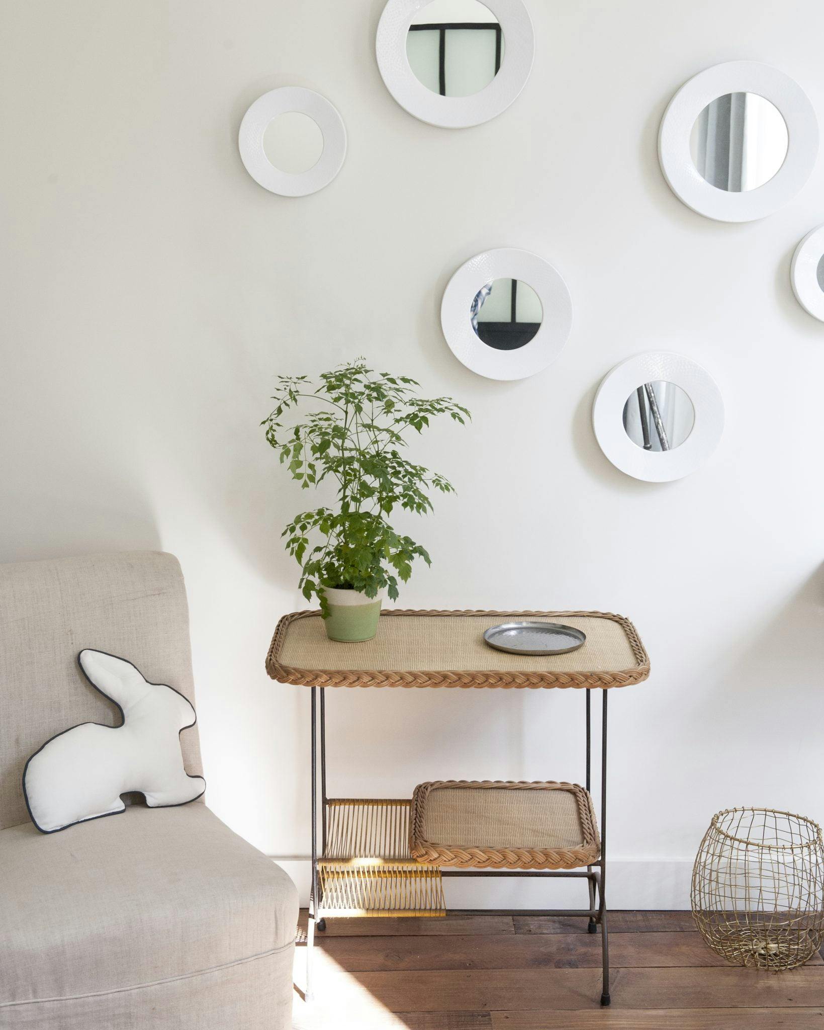 Detail of a wooden table, mirrors on a white wall.