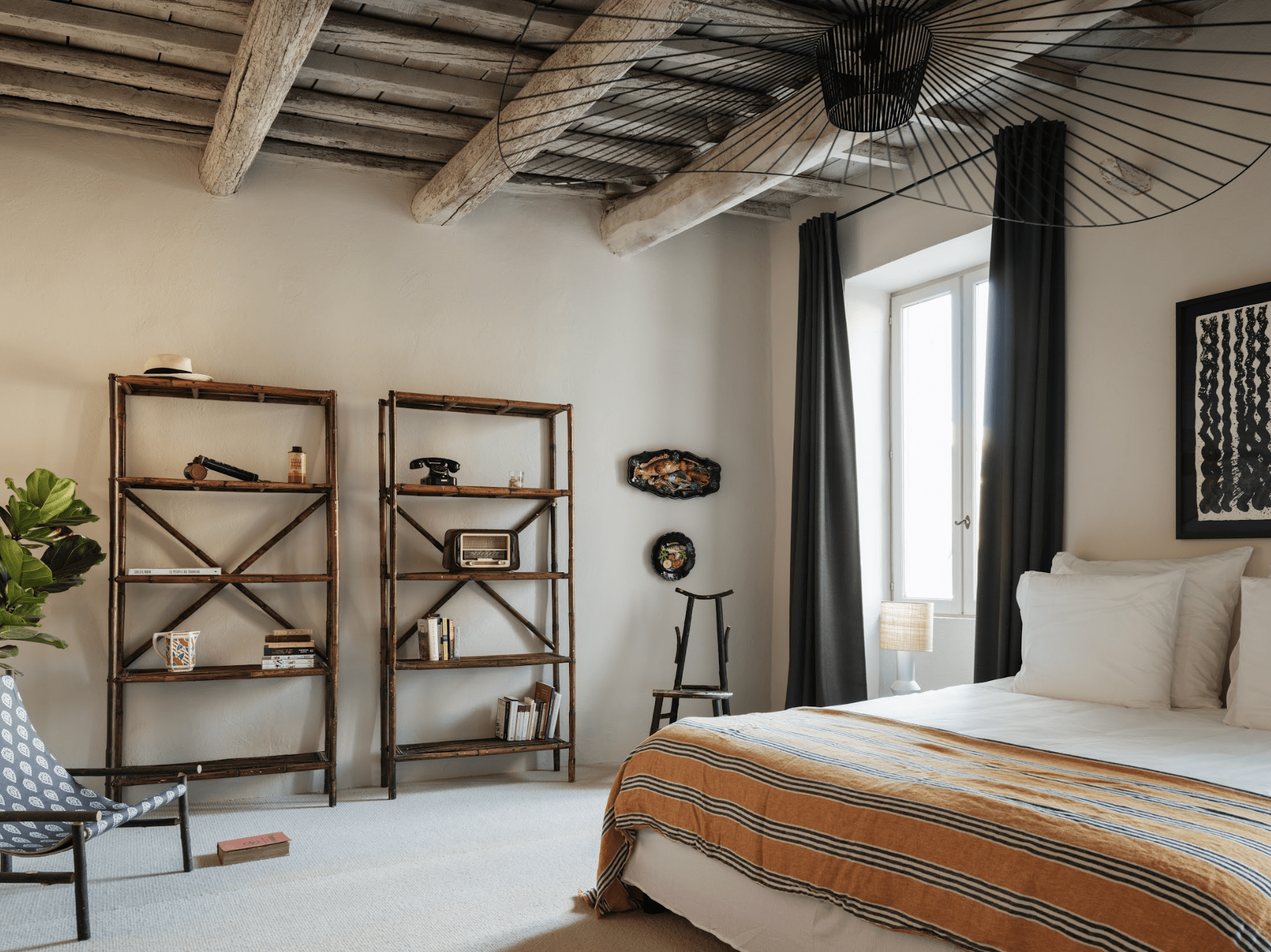 One of the bedrooms of the Maison des Remparts: bed, wooden bookshelf, beams.