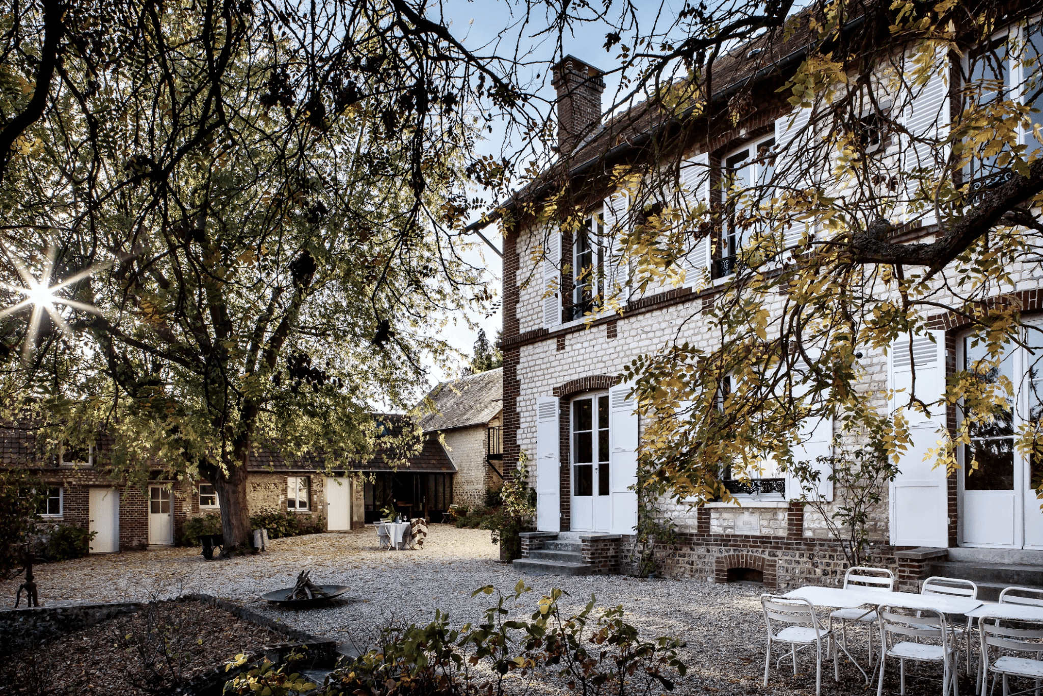 Cour de la maison en pierre, gravier et arbres
