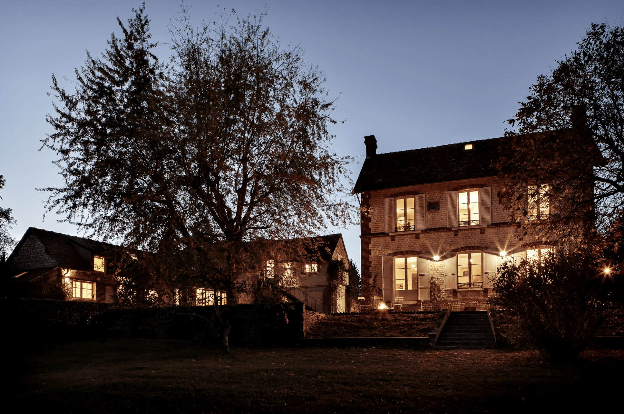 Vue de la maison depuis le jardin de nuit, arbre