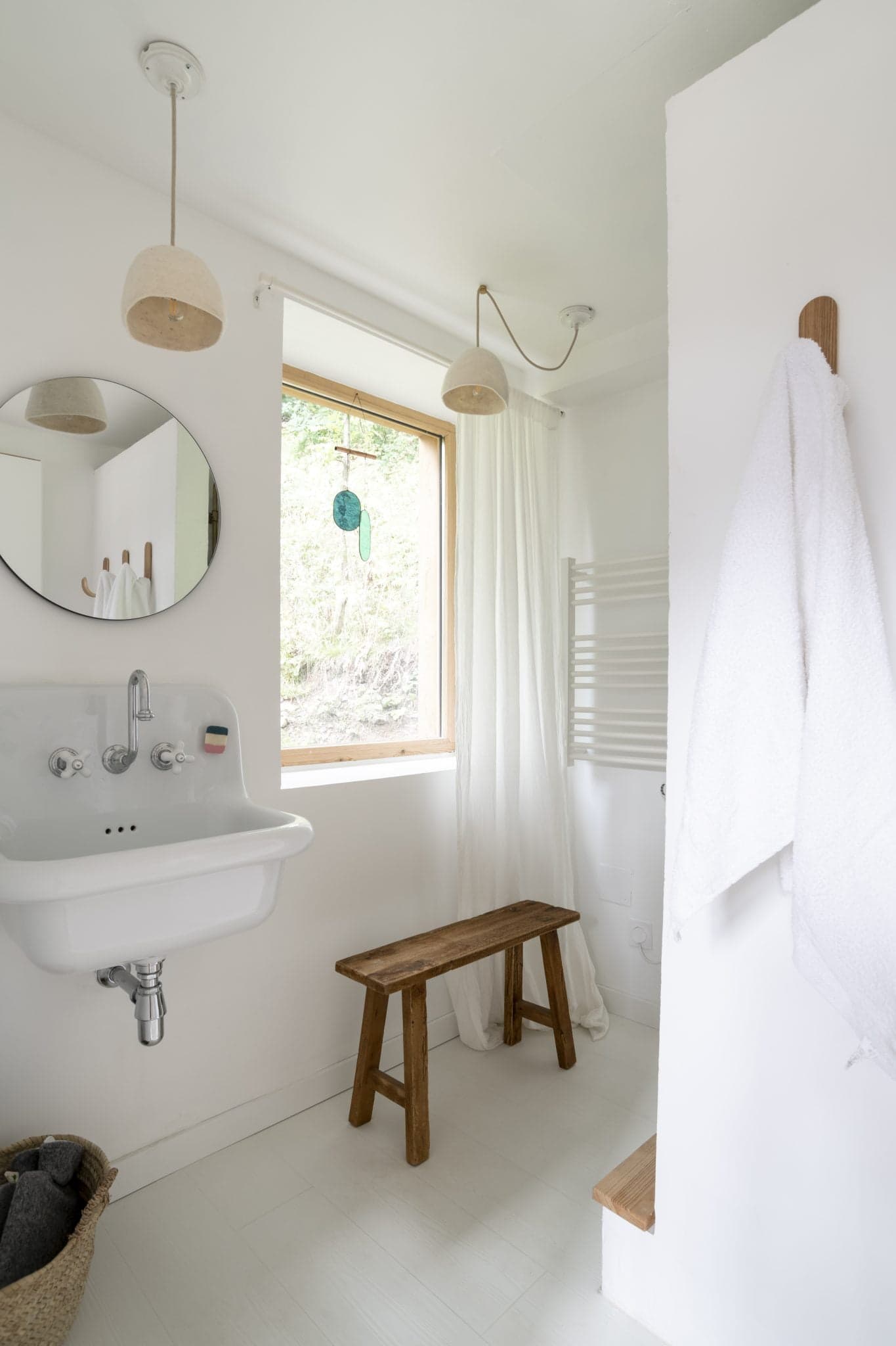 The bathroom of La Maison Refuge: white tiles, wooden bench