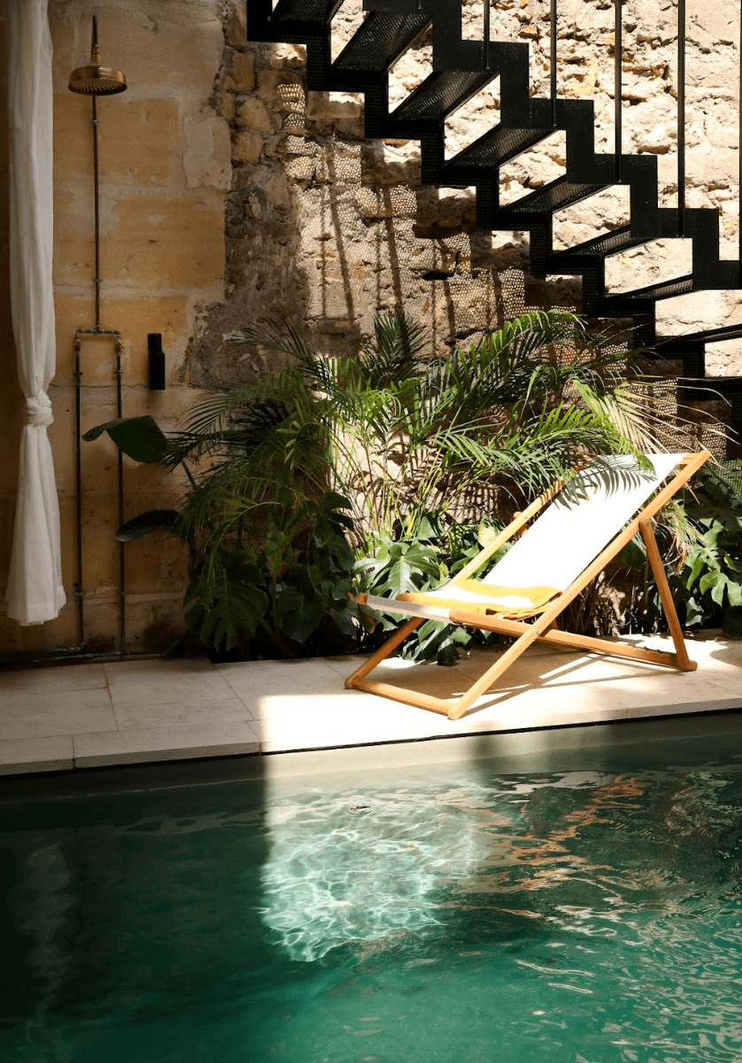 The sun lounger by the pool in front of the black wrought iron staircase