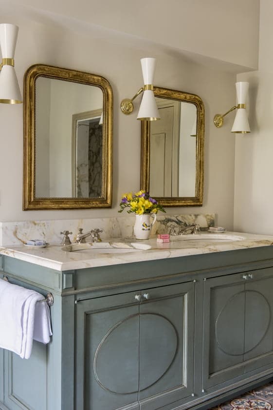 L'une des salles de bain du Mas le Gaudre : grands miroirs dorés, mobilier en bois vert d'eau