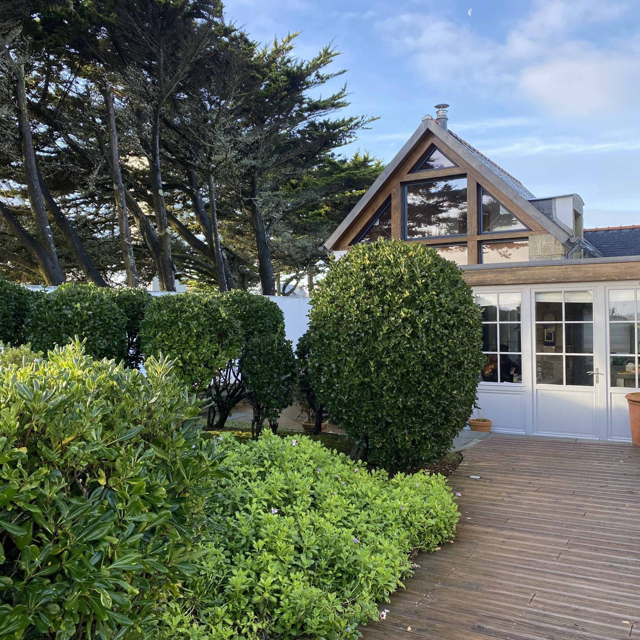 L'extérieur de Wabi Surf House : terrasse en bois, buissons et arbres