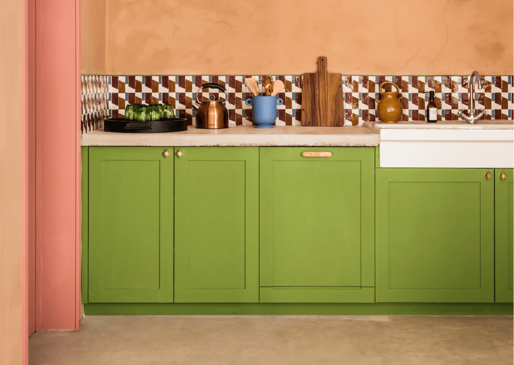 The kitchen of the holiday house at the Manufacture Royale de Lectoure: green furniture, orange wall