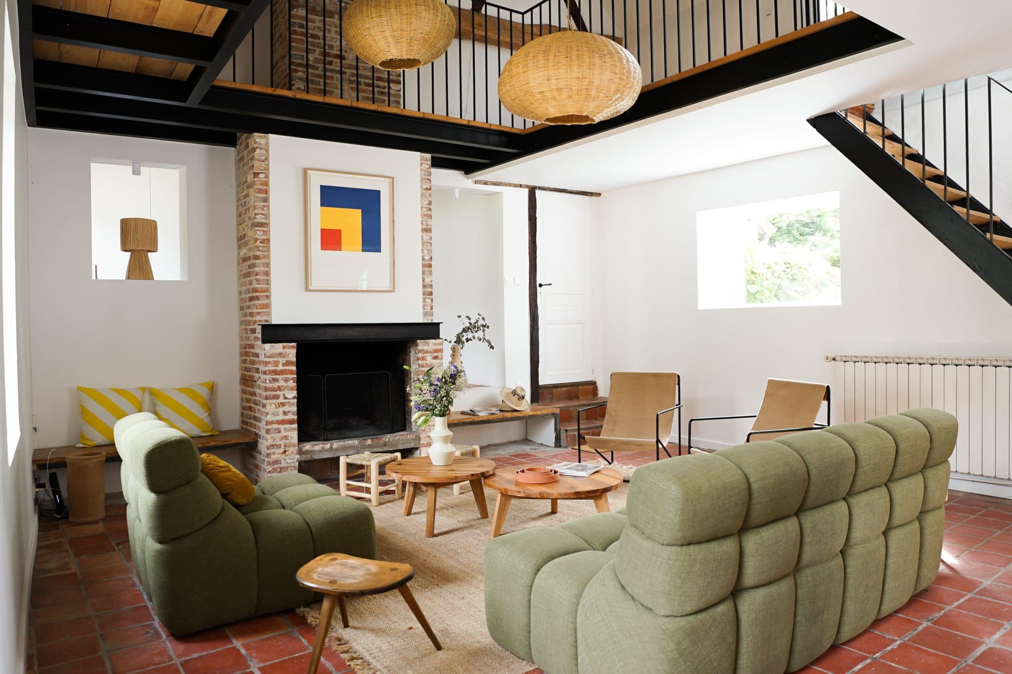 The living room: green sofas, fireplace, coffee table, pendant lights.