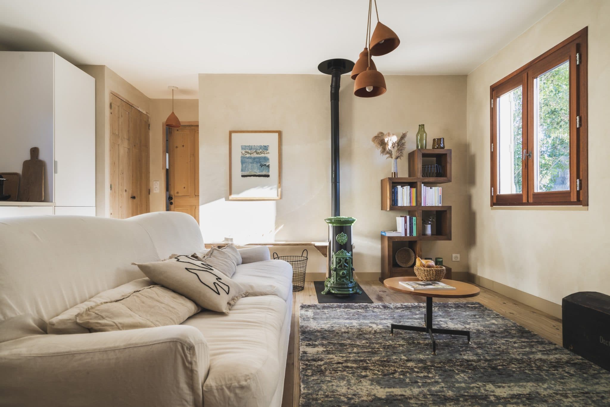 Le salon de la maison : poêle, canapé, tapis, tableaux
