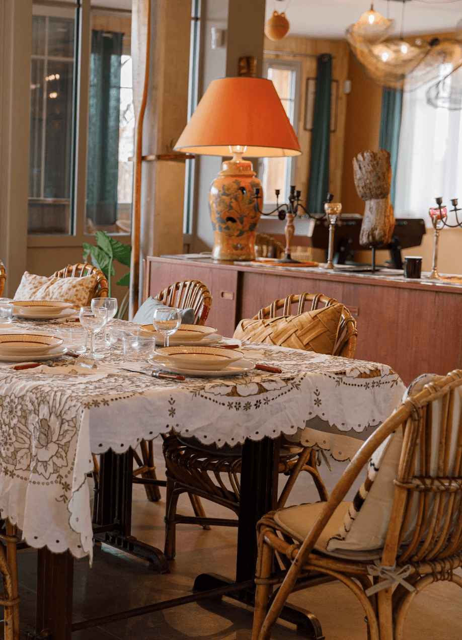 Table nappée et dressée, chaises en bois, luminaire orange