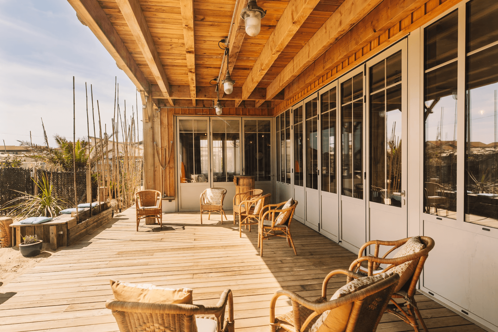 Terrasse en bois, fauteuils en rotin, baie vitrée