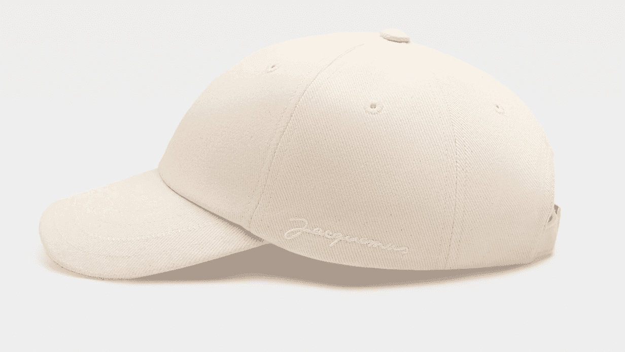 Casquette de baseball beige avec le logo "Jacquemus" brodé sur le côté. La casquette a une visière incurvée et se détache sur un fond blanc uni.