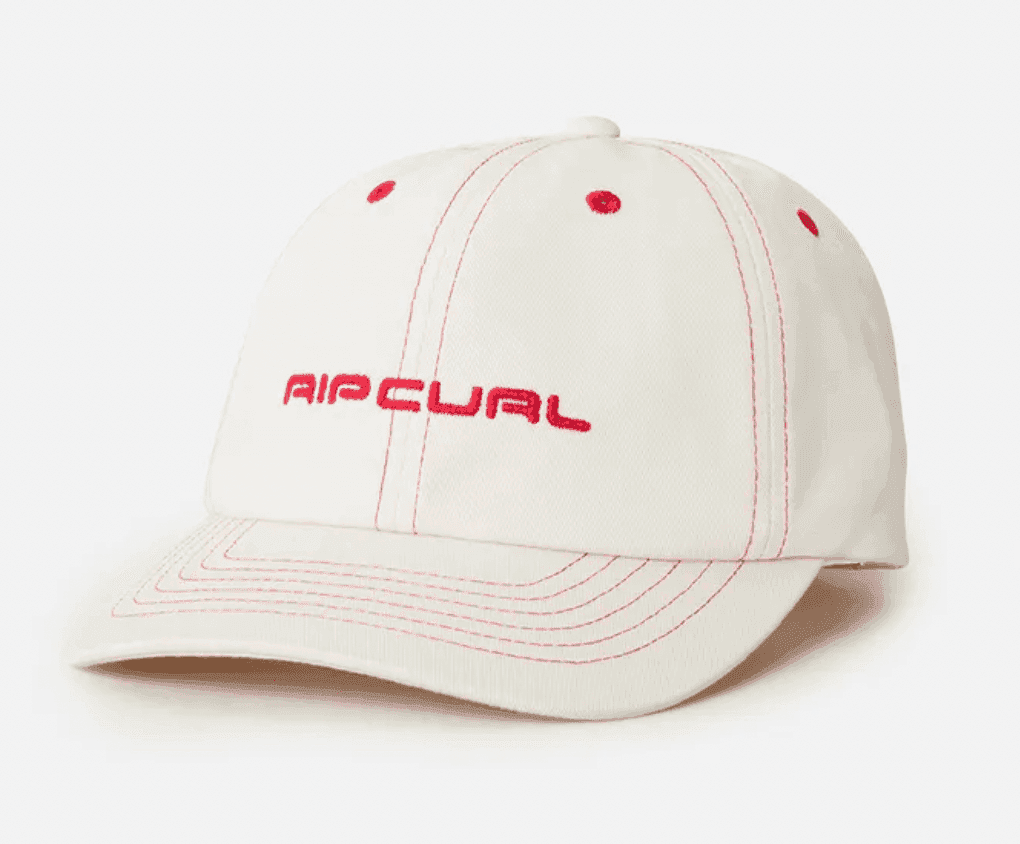 Une casquette de baseball blanche avec des coutures rouges et le mot « RIP CURL » brodé en rouge sur le devant. La casquette est présentée sur un fond blanc uni.