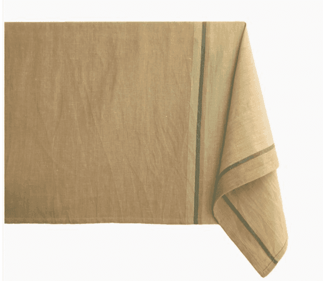Une nappe beige à la texture subtile est drapée sur une surface. Elle présente une bordure à double rayure verte et grise sur le bord droit, ajoutant une touche simple mais élégante.