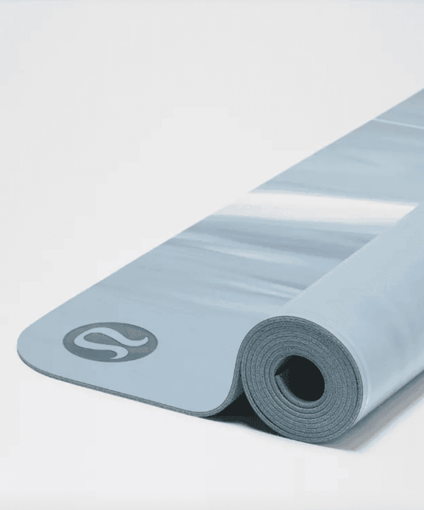 Un tapis de yoga bleu clair partiellement enroulé sur une surface blanche, avec un motif à rayures blanches subtiles et un logo dans un coin.