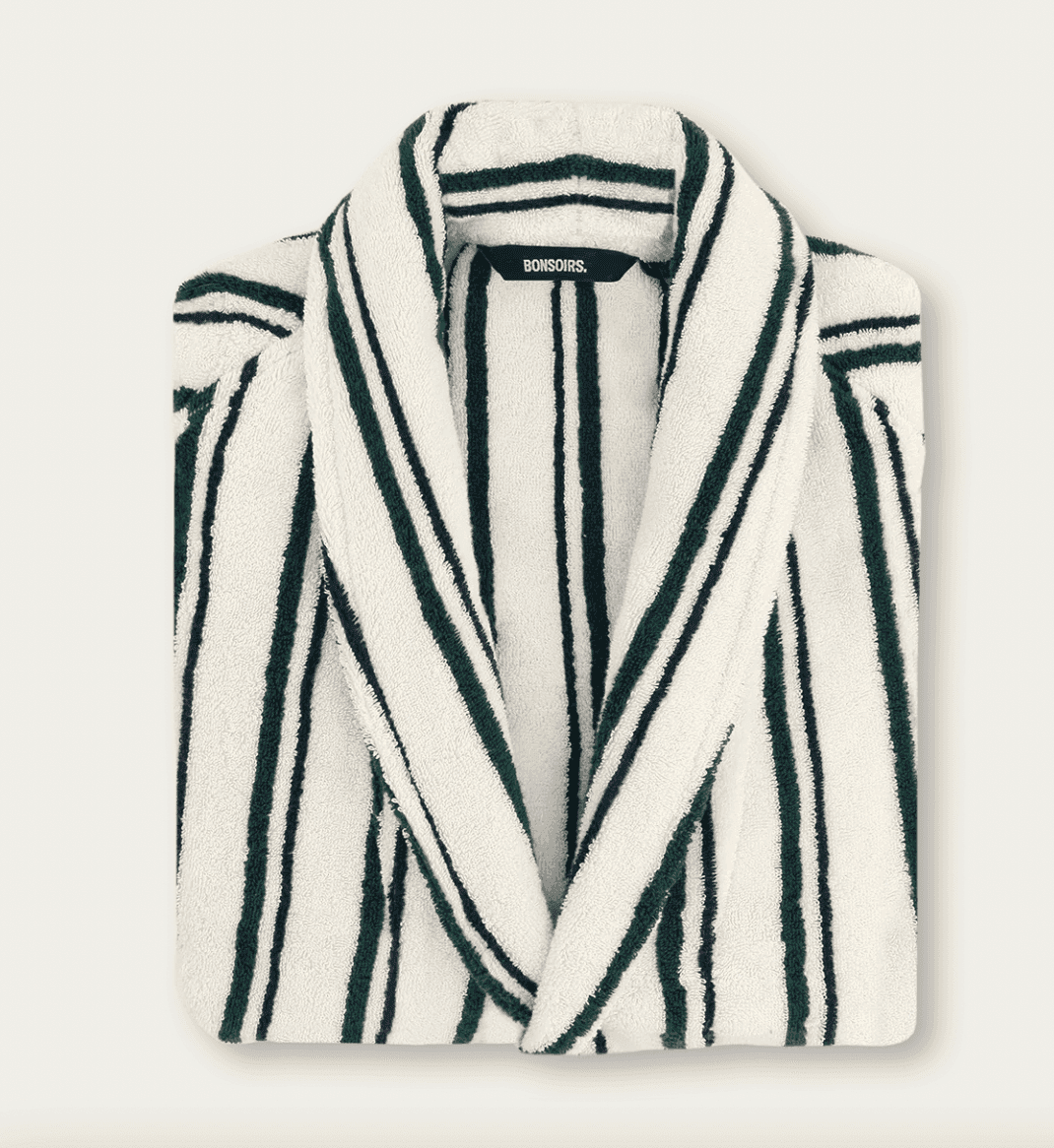 Peignoir blanc à rayures verticales vert foncé et noires, soigneusement plié. L'étiquette du col porte la mention "BONSOIRS". Le peignoir est présenté sur un fond uni de couleur claire.