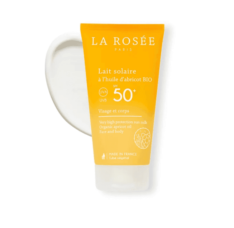 Tube jaune de crème solaire LA ROSÉE Paris avec SPF 50+. L’étiquette indique « Lait solaire à l’huile d’abricot BIO » pour le visage et le corps. Contient de l'huile d'abricot biologique. Fond blanc.