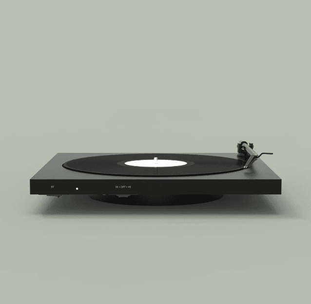 Une platine vinyle noire minimaliste repose sur un fond gris neutre, avec un disque vinyle noir et une étiquette blanche. Le bras de lecture est positionné sur le disque, prêt à lire la musique.