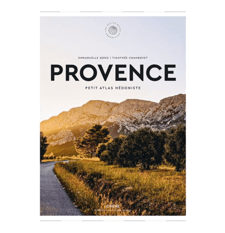 Couverture du livre intitulée « Provence Petit Atlas Hédoniste » avec une photo panoramique d'une route sinueuse, d'oliviers et de montagnes sous un ciel doré. Auteurs : Emmanuelle Oddo et Timothée Chambovet.