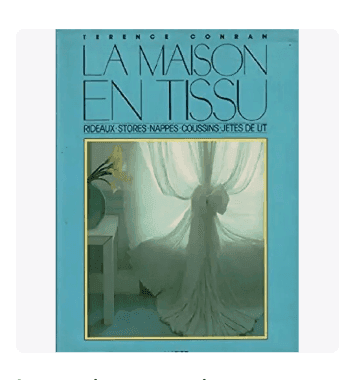 Couverture du livre "La Maison en Tissu" de Terence Conran, avec un fond bleu clair et une photo d'une pièce ensoleillée avec des rideaux blancs transparents, une table avec une lampe et un vase avec des fleurs blanches.