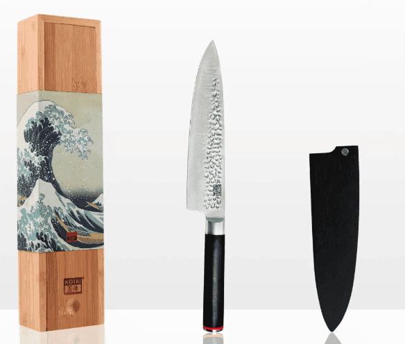 Un couteau de chef japonais avec une lame texturée et un manche noir se dresse debout entre une boîte en bois décorative présentant un motif de vague et un étui à couteau noir, le tout sur un fond blanc.